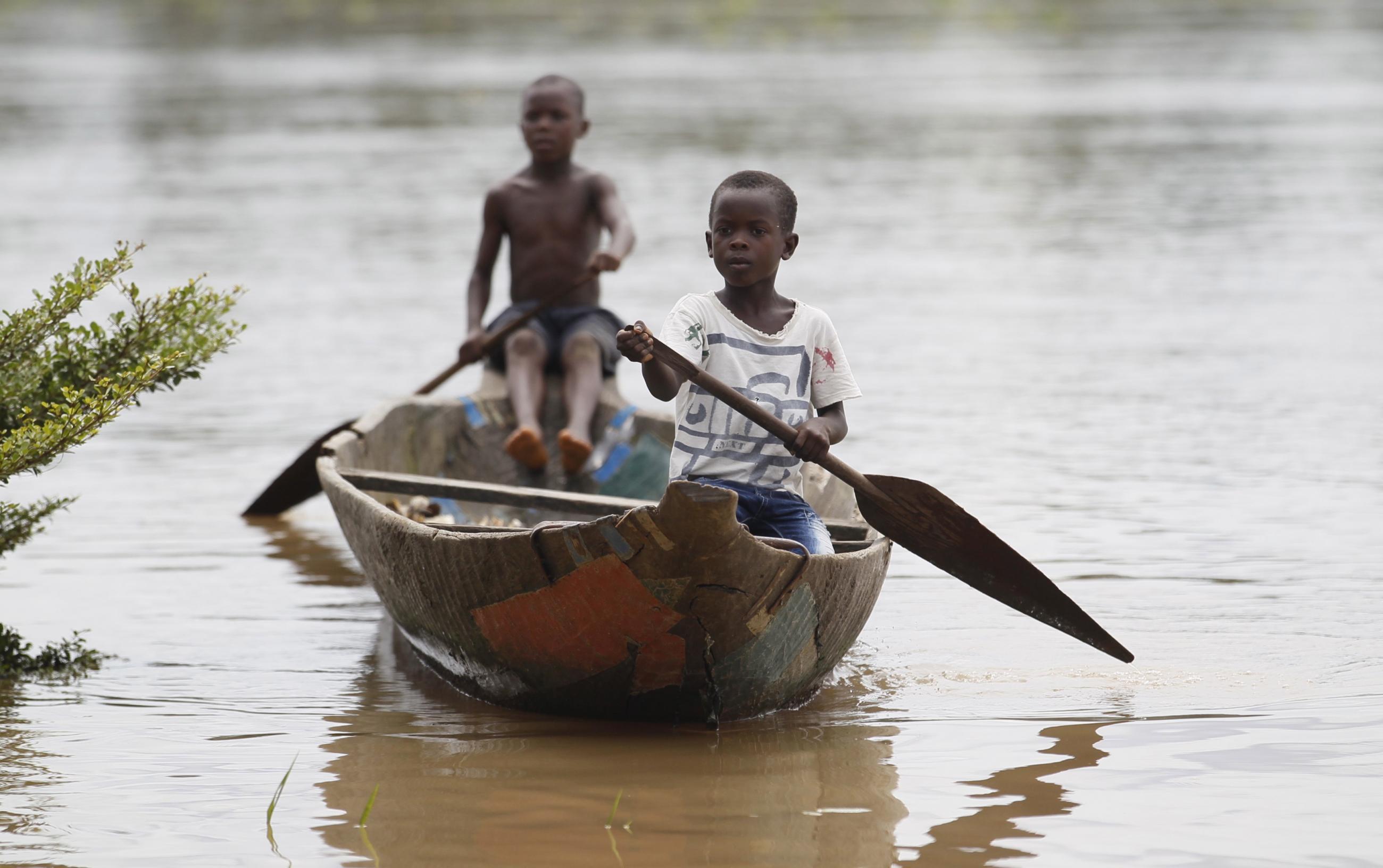 Two young boys paddle a canoe near the shore of the Nun River in Yeneka village in Nigeria's Bayelsa state on October 8, 2015.