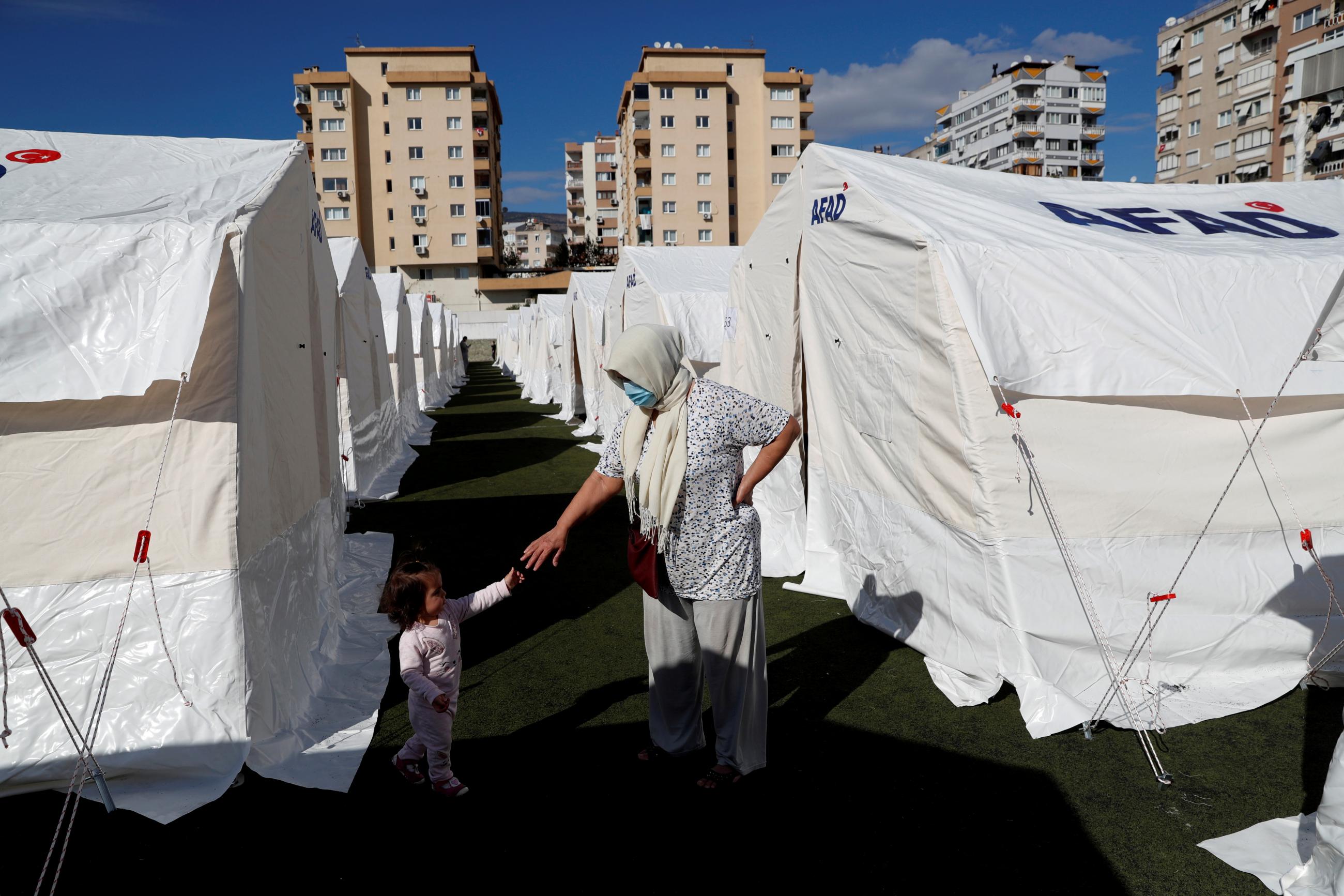 A woman and a child stand amid a tent city set up by Turkey's Disaster and Emergency Management Presidency (AFAD) after an earthquake in the Aegean port city of Izmir, Turkey, November 1, 2020. 