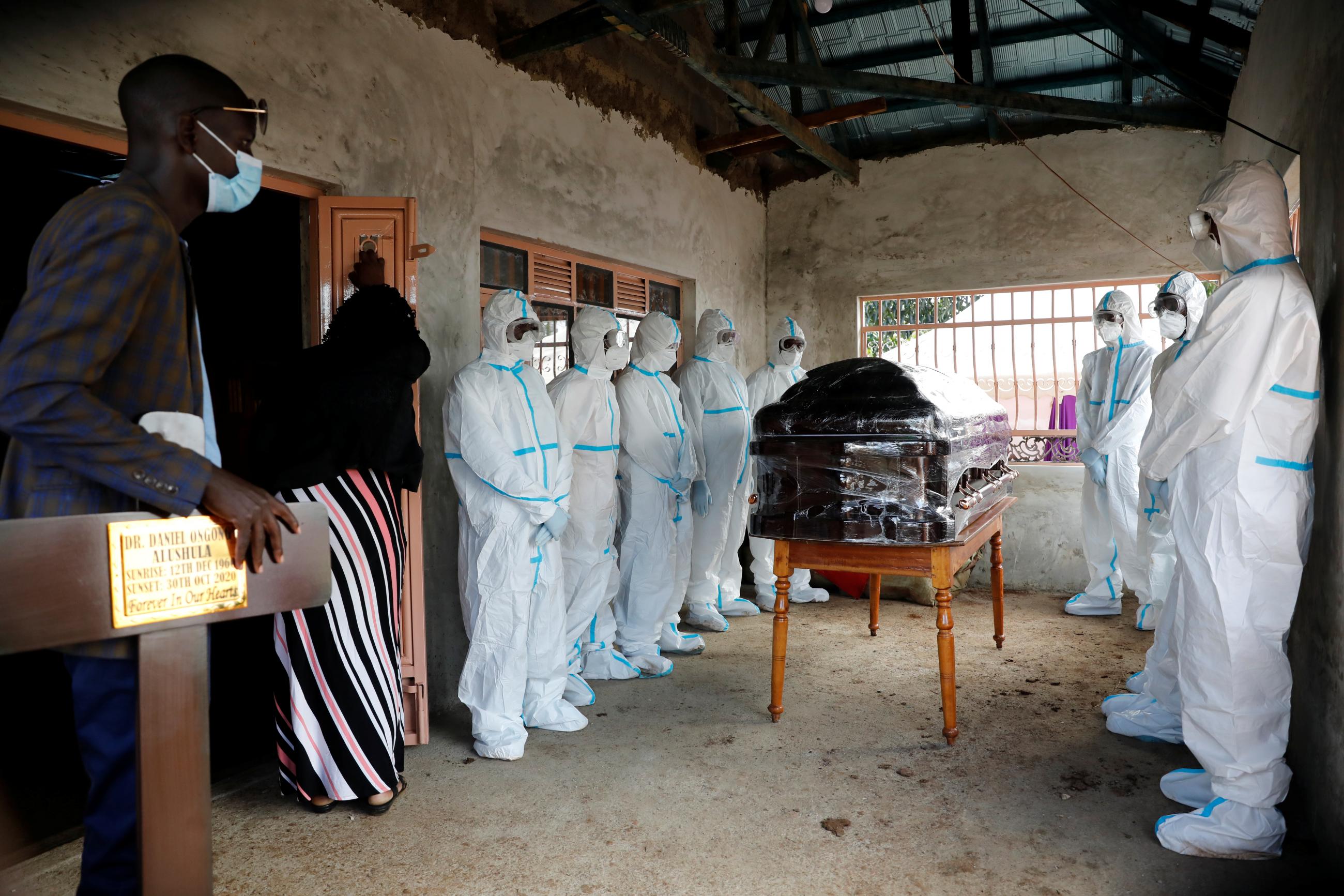 Men dressed in protective suits stand around the coffin of Kenyan doctor Daniel Alushula who died of coronavirus disease (COVID-19), during his funeral in the village of Khumusalaba, in Kakamega county, Kenya November 13, 2020