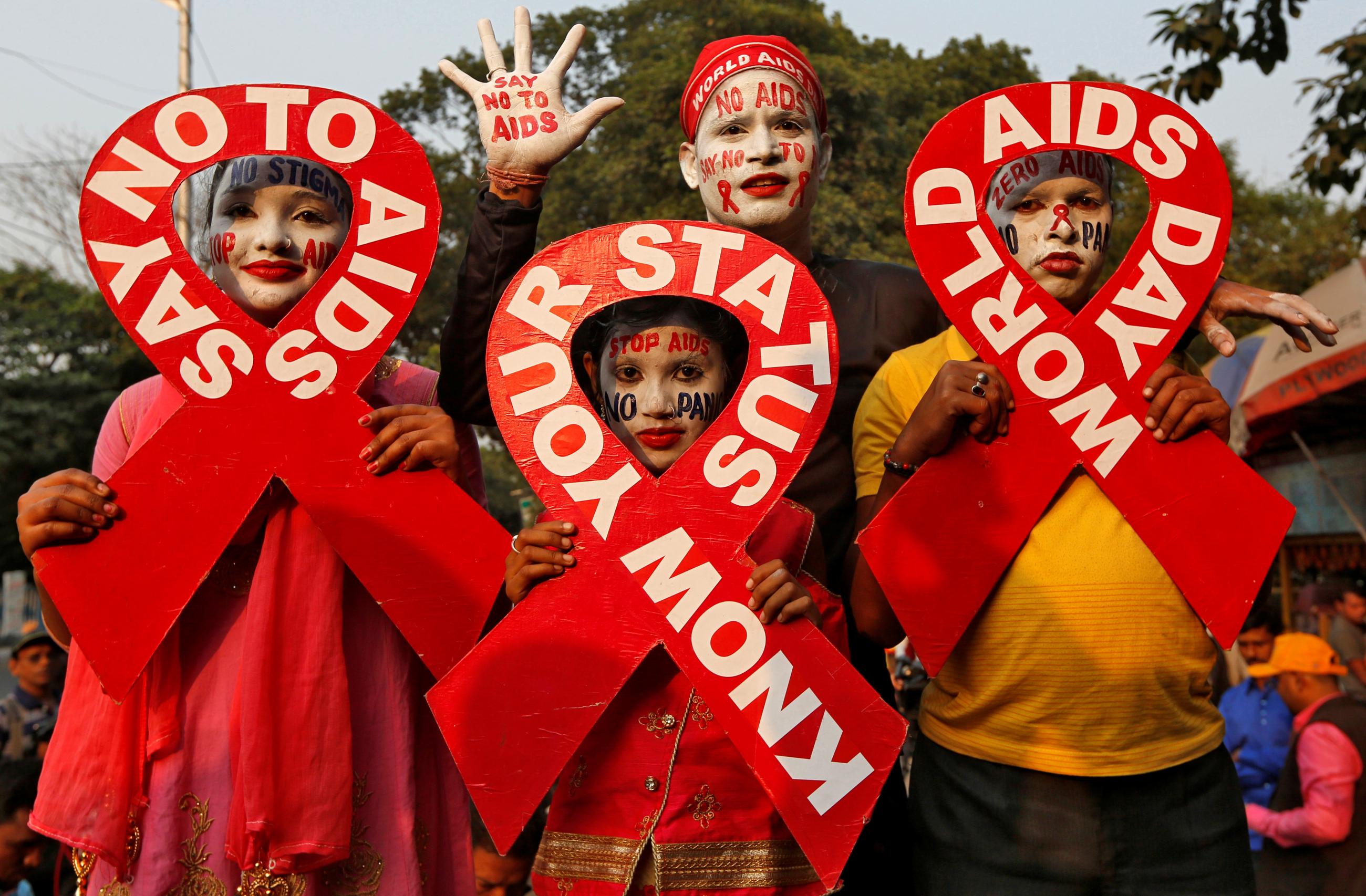 People with painted faces hold ribbon cut-outs as they pose during an HIV/AIDS awareness campaign on the eve of World AIDS Day in Kolkata, India, November 30, 2018