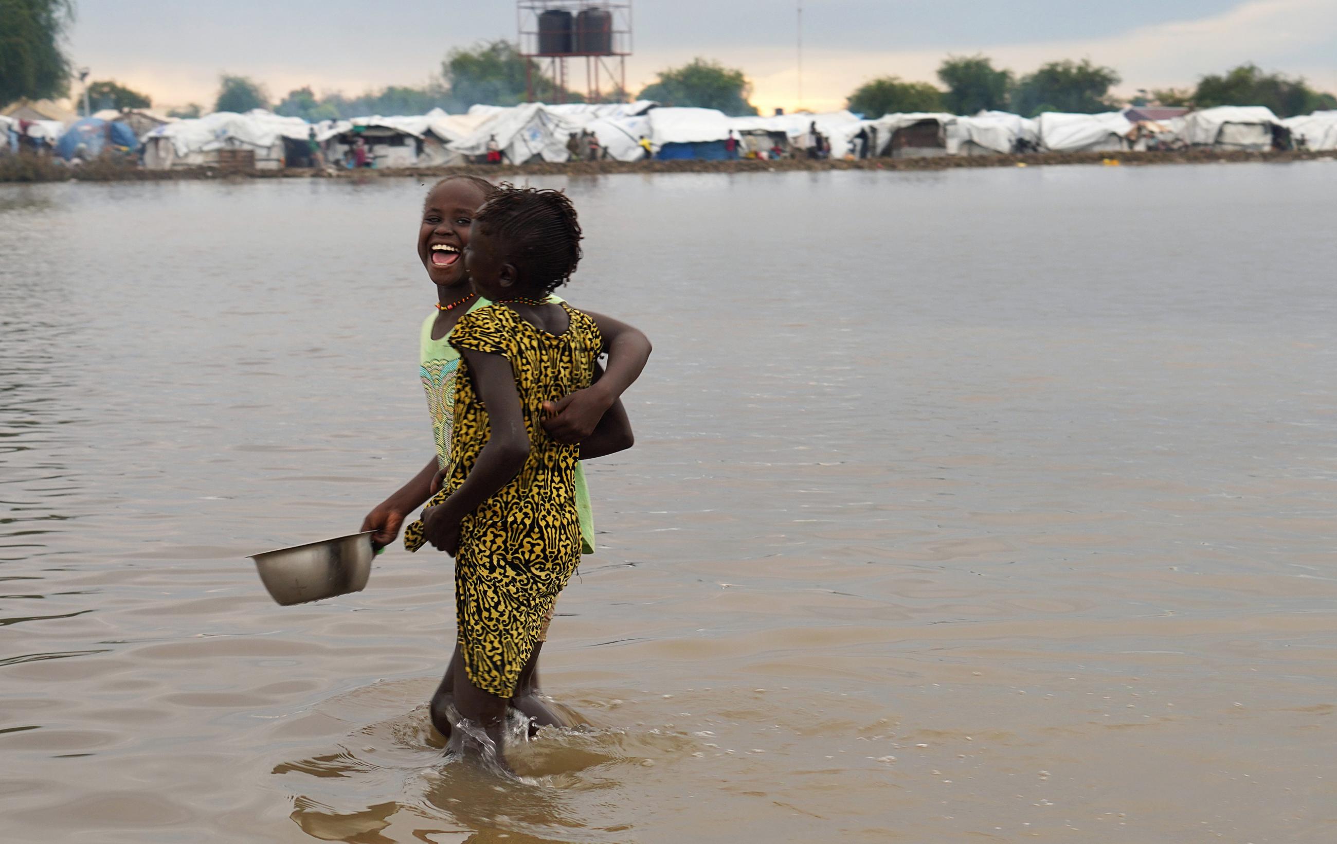 Displaced children laugh as they wade through floodwaters after the River Nile broke the dykes in Pibor, Greater Pibor Administrative Area, South Sudan October 6, 2020.