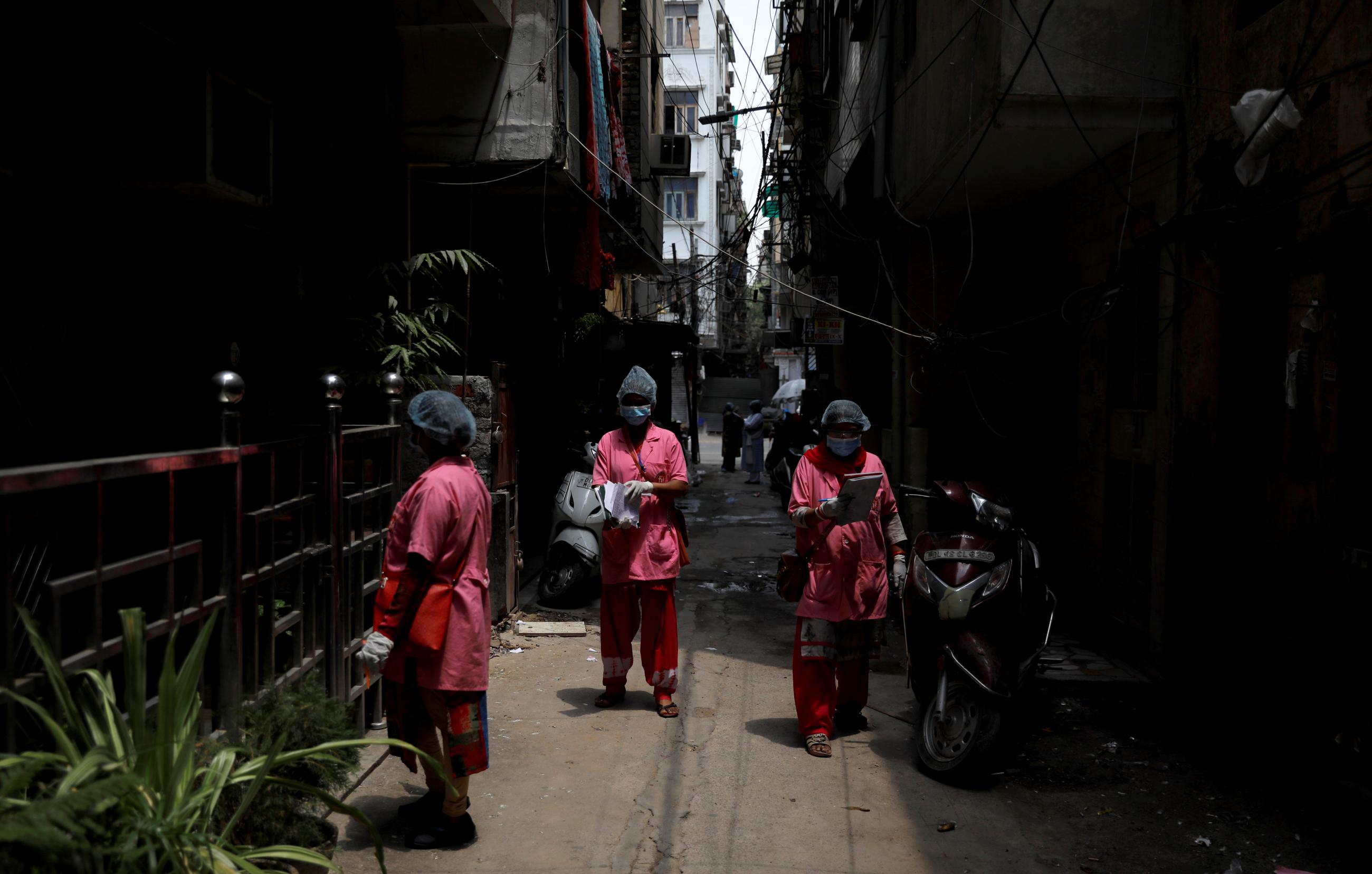 Accredited Social Health Activist) workers, community health workers instituted by the government of India's Ministry of Health and Family Welfare, are seen in an alley as they conduct a door-to-door survey for the coronavirus disease (COVID-19), amidst its spread in New Delhi, India June 26, 2020