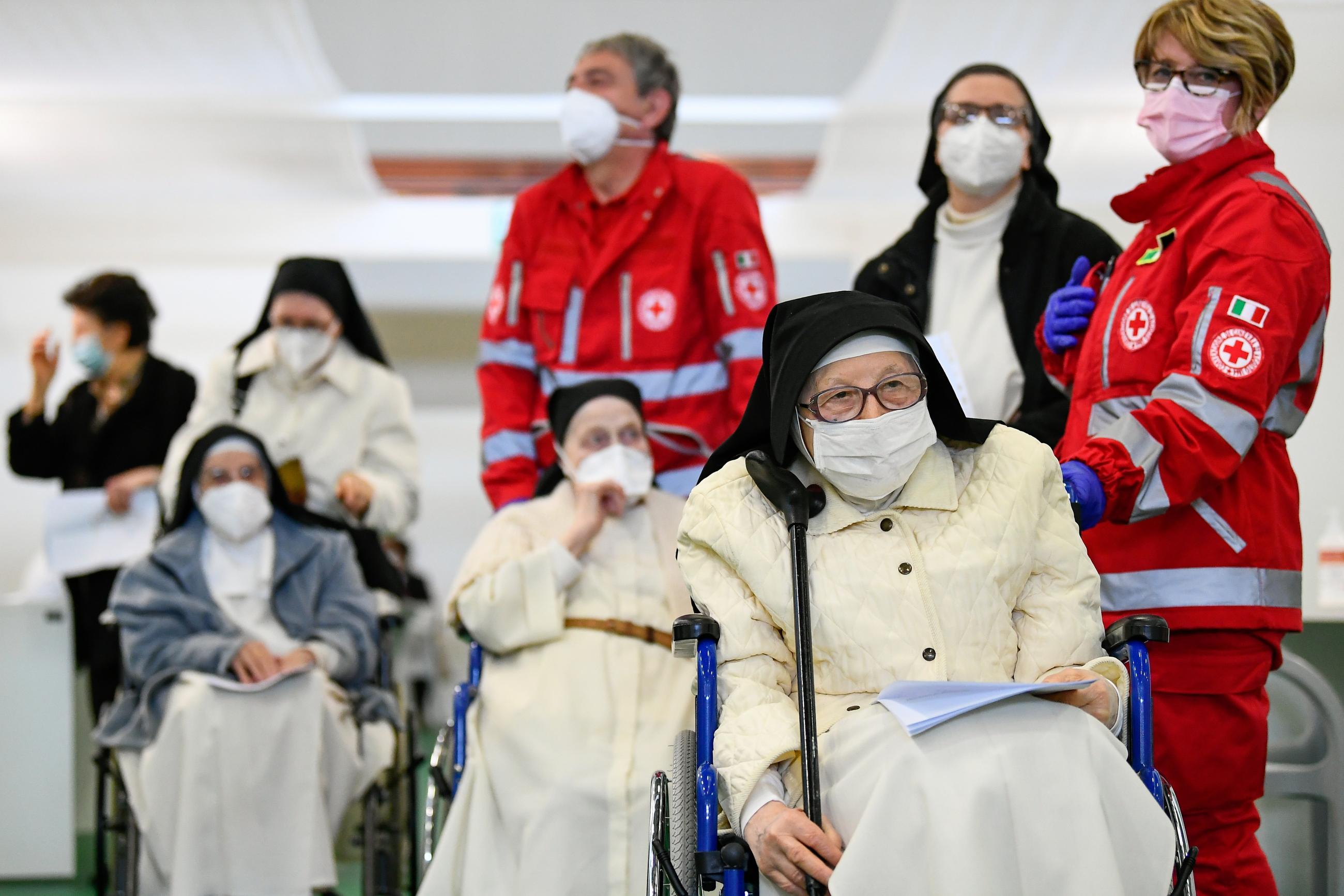 Members of the Red Cross stand next to nuns that wait to receive the coronavirus disease vaccine in Bergamo, Italy on March 1, 2021.