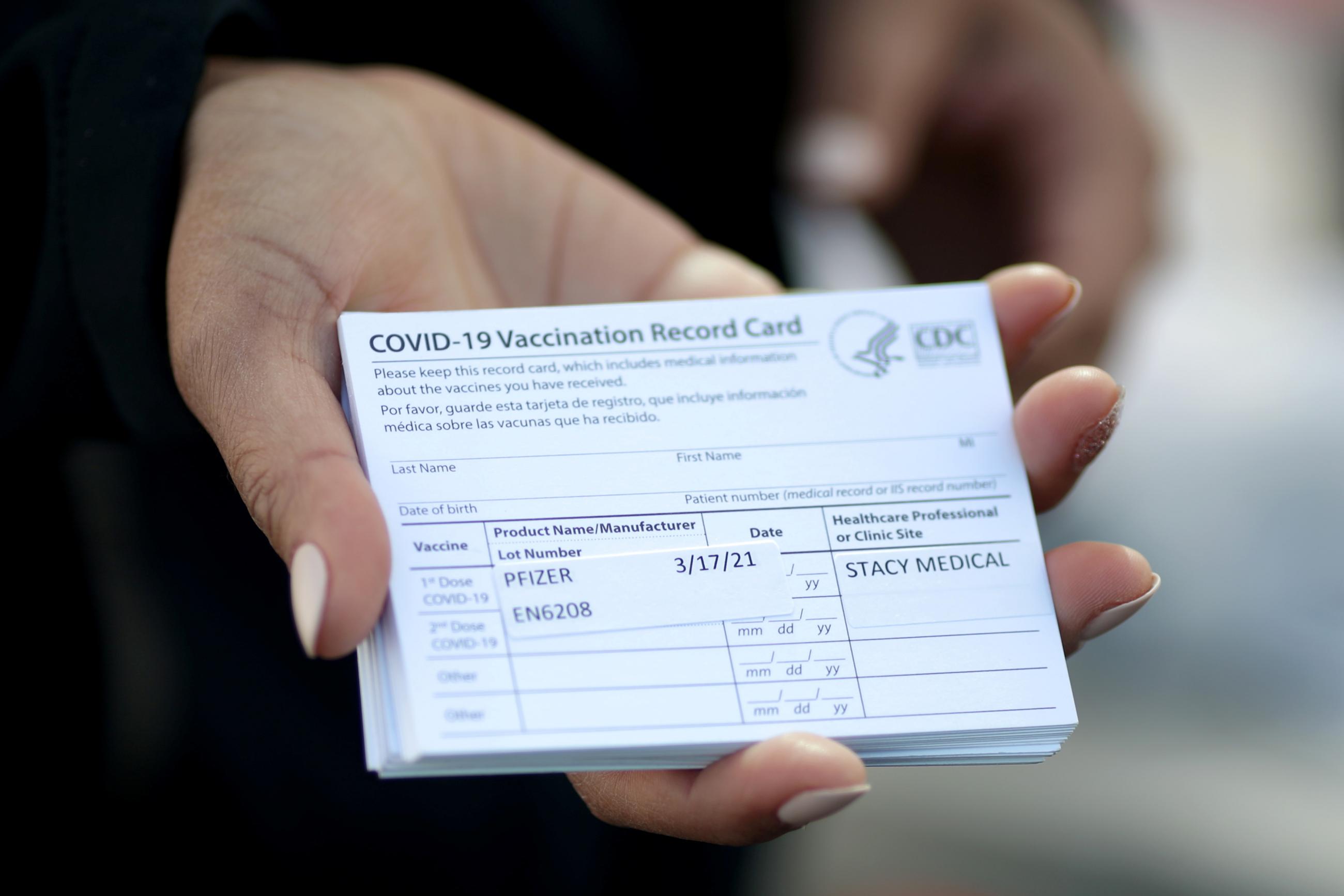 A medical worker holds Pfizer coronavirus disease vaccination cards at a mobile vaccination drive in Los Angeles, California on March 17, 2021. 