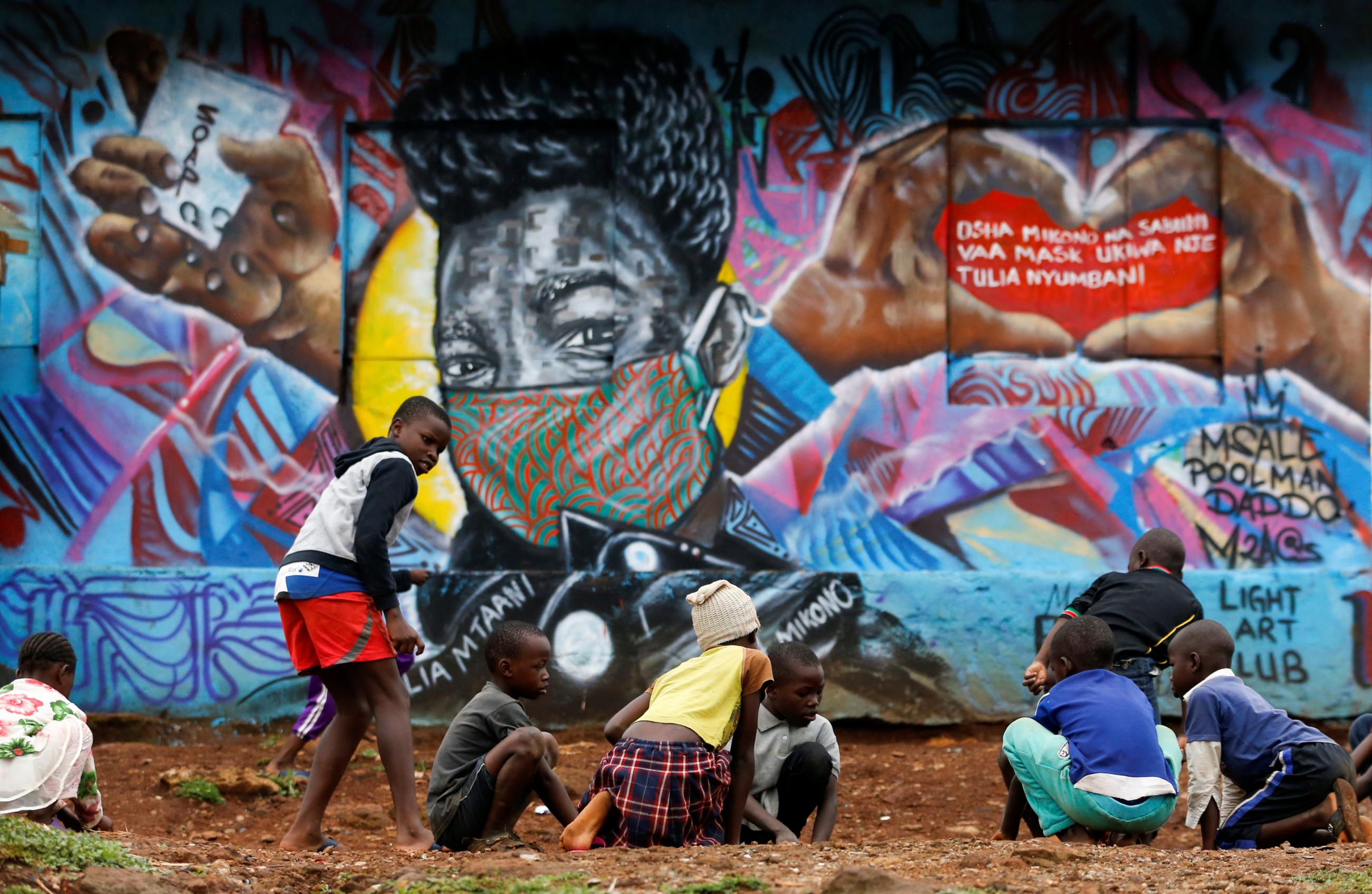 Children play in front of a graffiti by Mathare Roots's youth group that advocates against the spread of the coronavirus disease (COVID-19), at the Mathare Valley slum, in Nairobi, Kenya April 19, 2020.