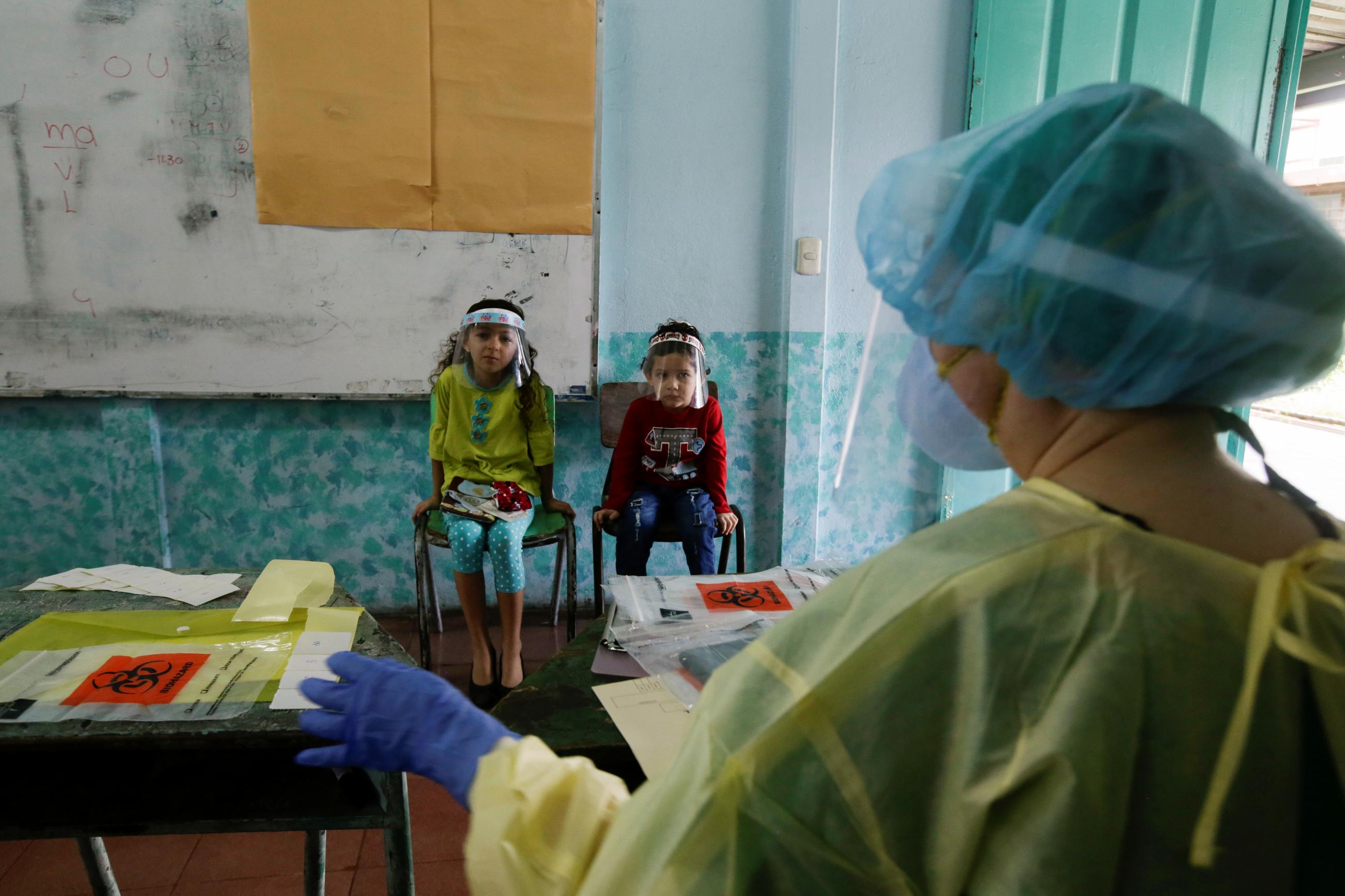 Children wait for a coronavirus (COVID-19) swab test in San Jose, Costa Rica on June 26, 2020. REUTERS/Juan Carlos Ulate