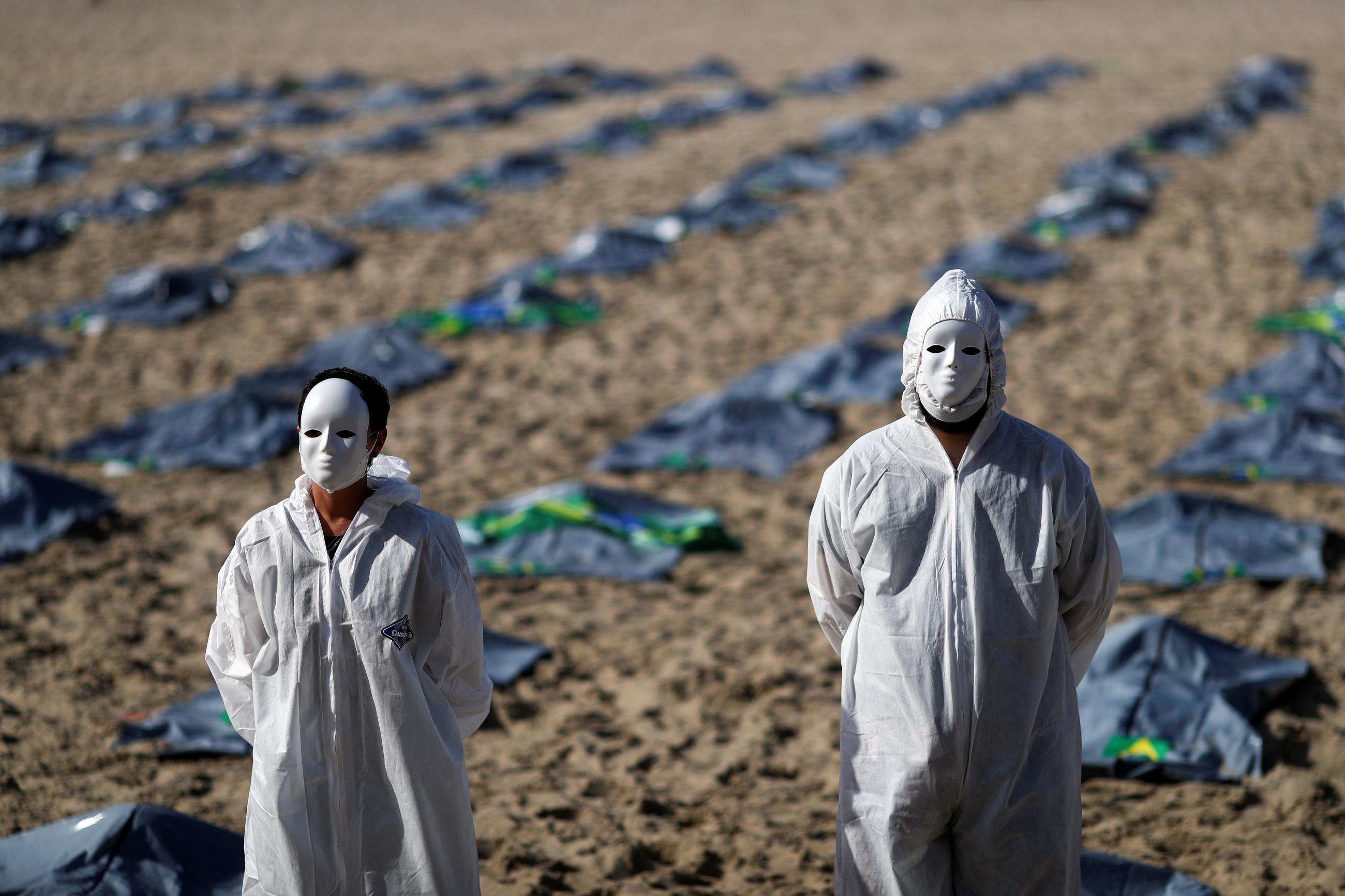 Activists from NGO Rio de Paz wear masks and PPE as they display hundreds of plastic bags, representing dead bodies, during a protest against Jair Bolsonaro's COVID-19 policies, amid the coronavirus disease (COVID-19) outbreak, in Copacabana beach, in Rio de Janeiro, Brazil, April 30, 2021.
