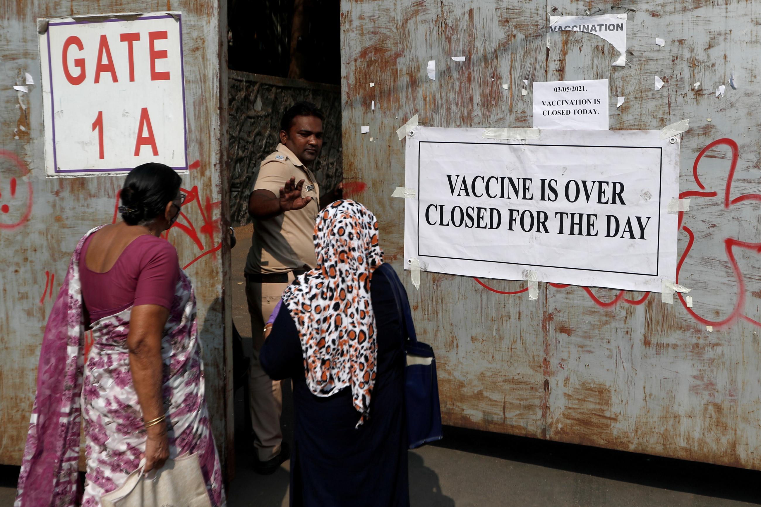 A policeman asks people who came to receive a dose of a coronavirus disease (COVID-19) vaccine to leave as they stand outside the gate of a vaccination centre which was closed due to unavailability of the supply of COVID-19 vaccine, in Mumbai, India, May 3, 2021.