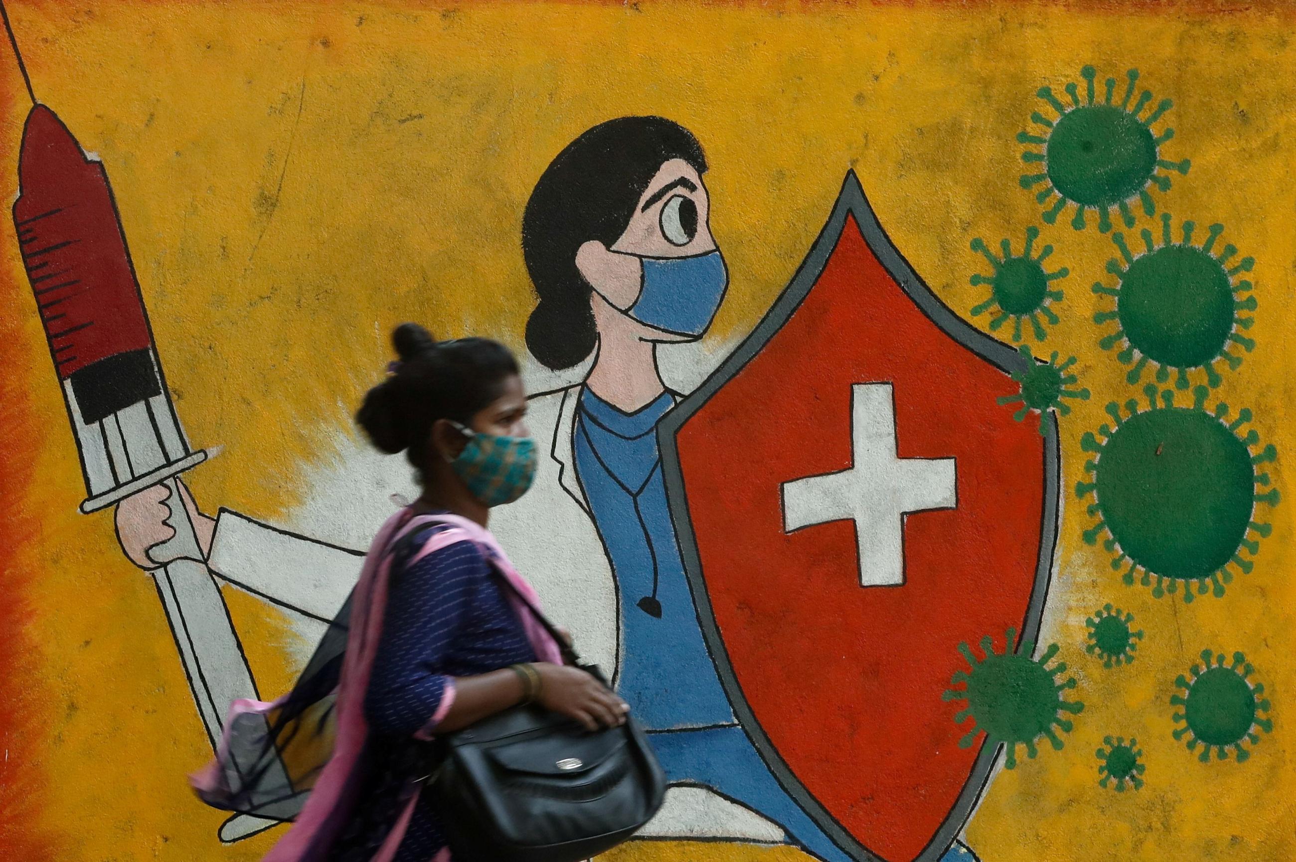 A woman walks past a graffiti on a street, amidst the spread of the coronavirus disease (COVID-19) in Mumbai, India, May 10, 2021.
