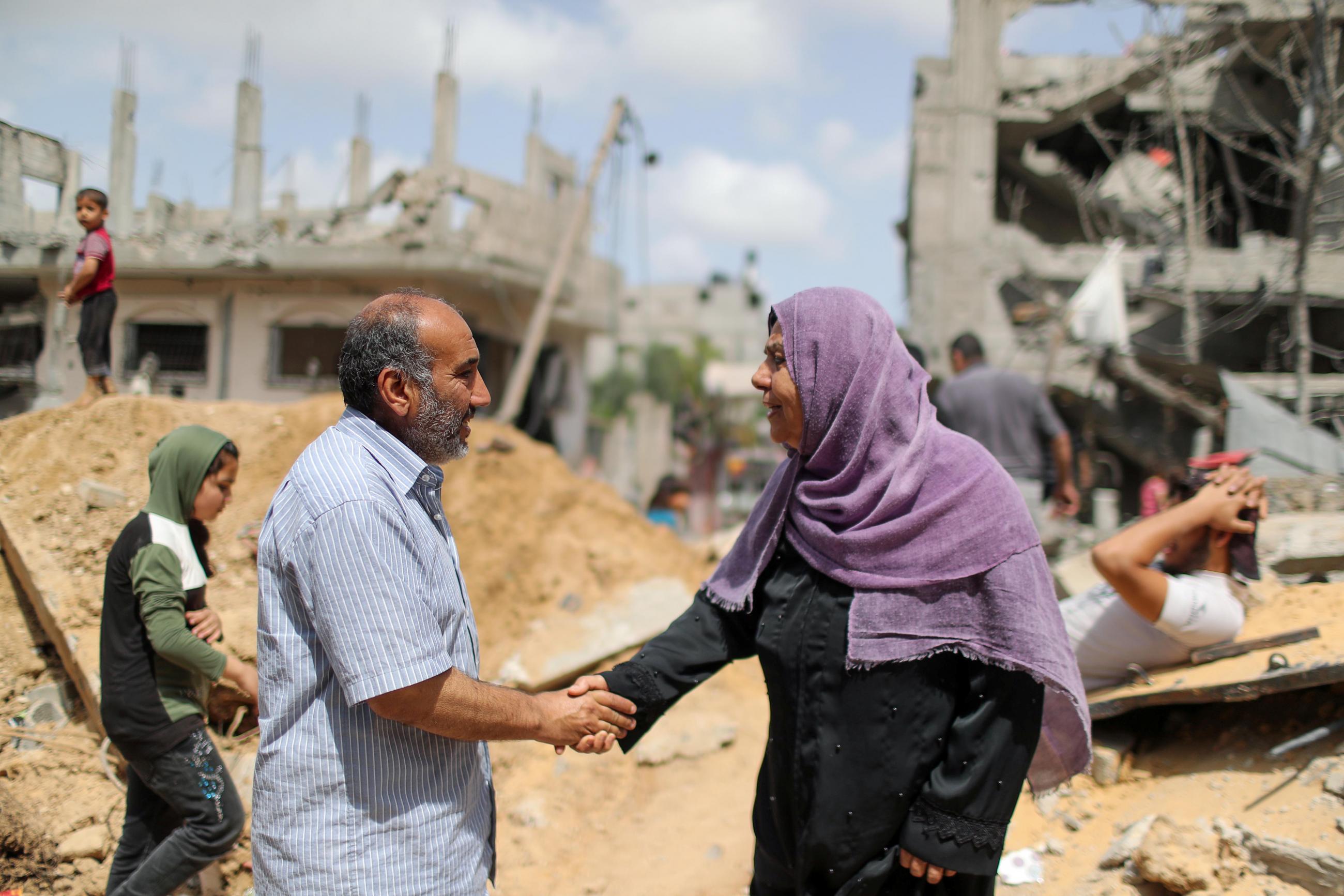 A Palestinian man and a Palestinian woman from shake hands after returning to their destroyed houses following an Israel-Hamas truce, in Beit Hanoun in the northern Gaza Strip on May 21, 2021. REUTERS/Mohammed Salem