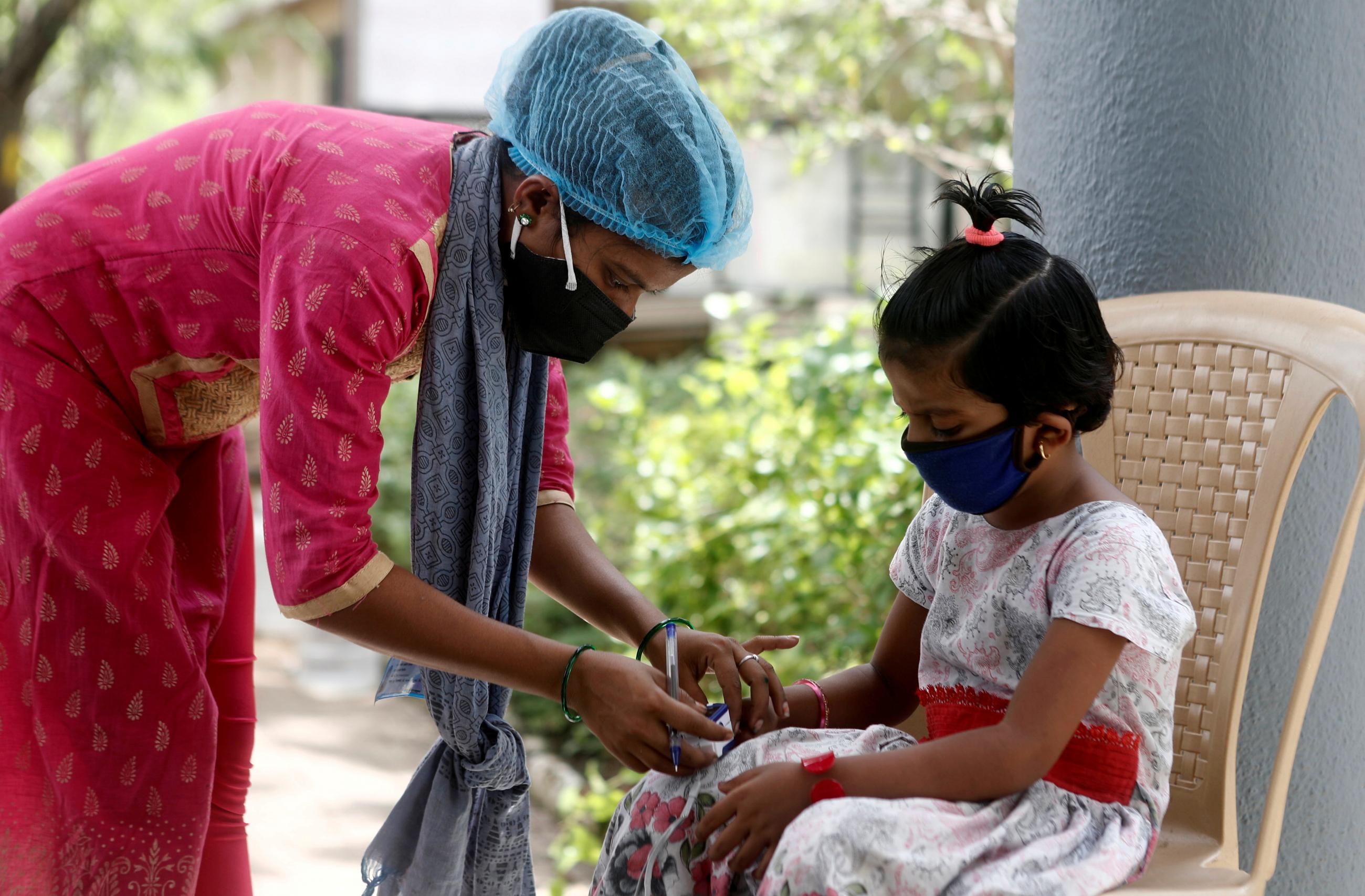 A nurse leans down to check a young coronavirus patient's pulse before she is admitted into a school turned COVID-19 care facility on the outskirts of Mumbai, India on May 24, 2021.