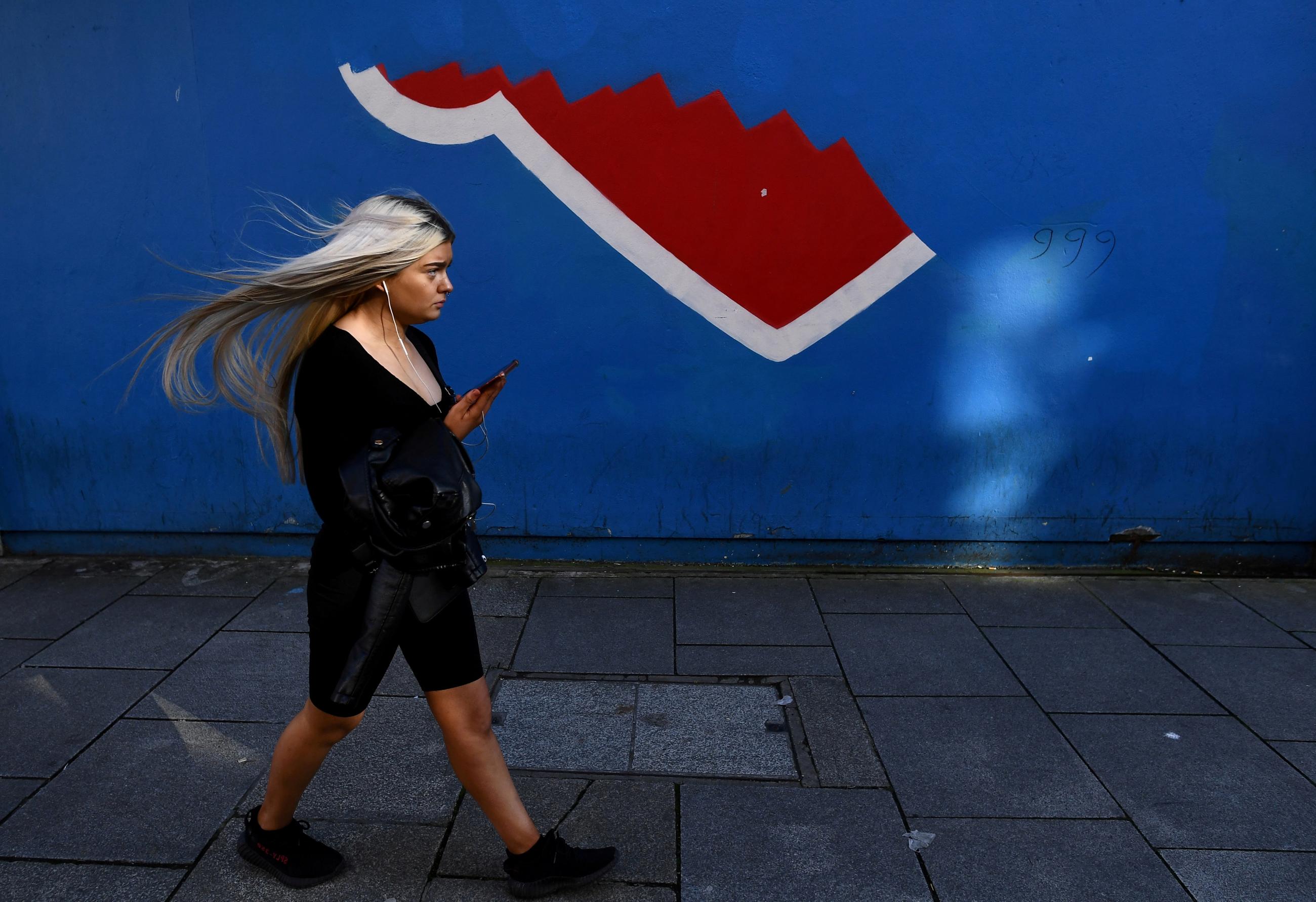A woman walks past the remains of a blue and red abortion rights mural in Dublin, Ireland on March 16, 2021.