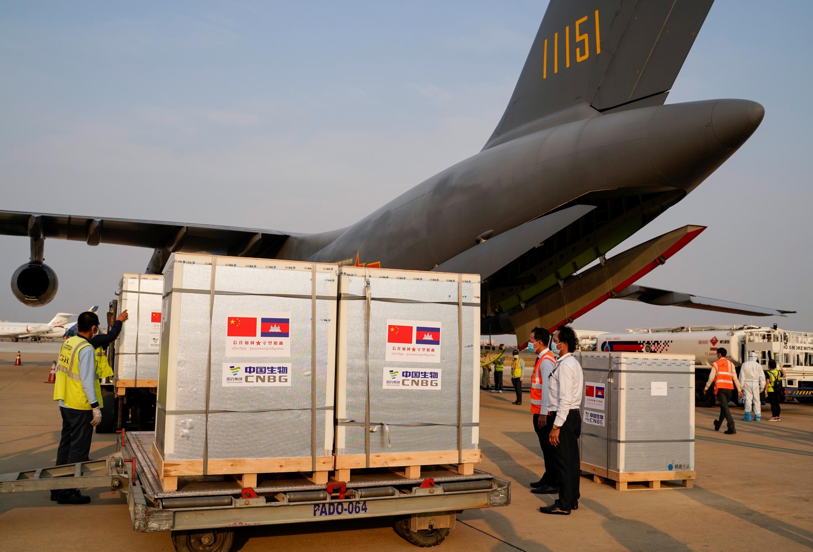 Workers stand next to the shipment of 600,000 doses of coronavirus disease (COVID-19) vaccines donated by China, at Phnom Penh International Airport, in Phnom Penh, Cambodia on February 7, 2021