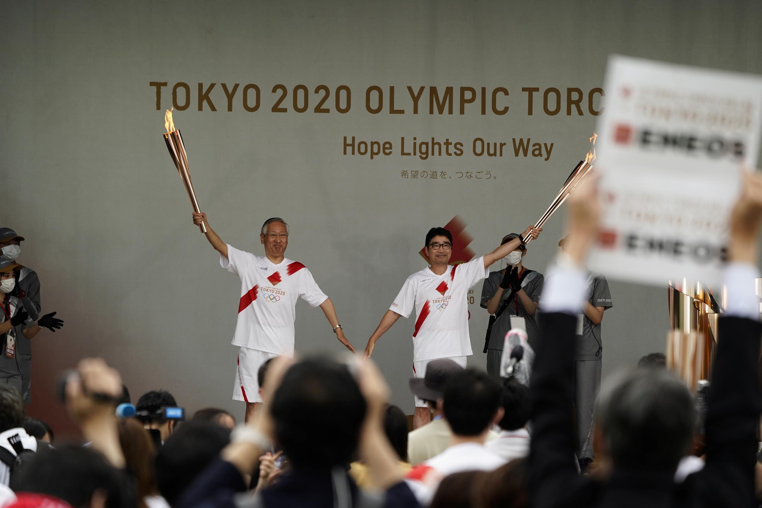 Tokyo's torchbearers pose during a lighting ceremony after their relay on a public road was canceled due to the COVID pandemic, at the Tokyo 2020 Olympics in Japan on July 9, 2021.