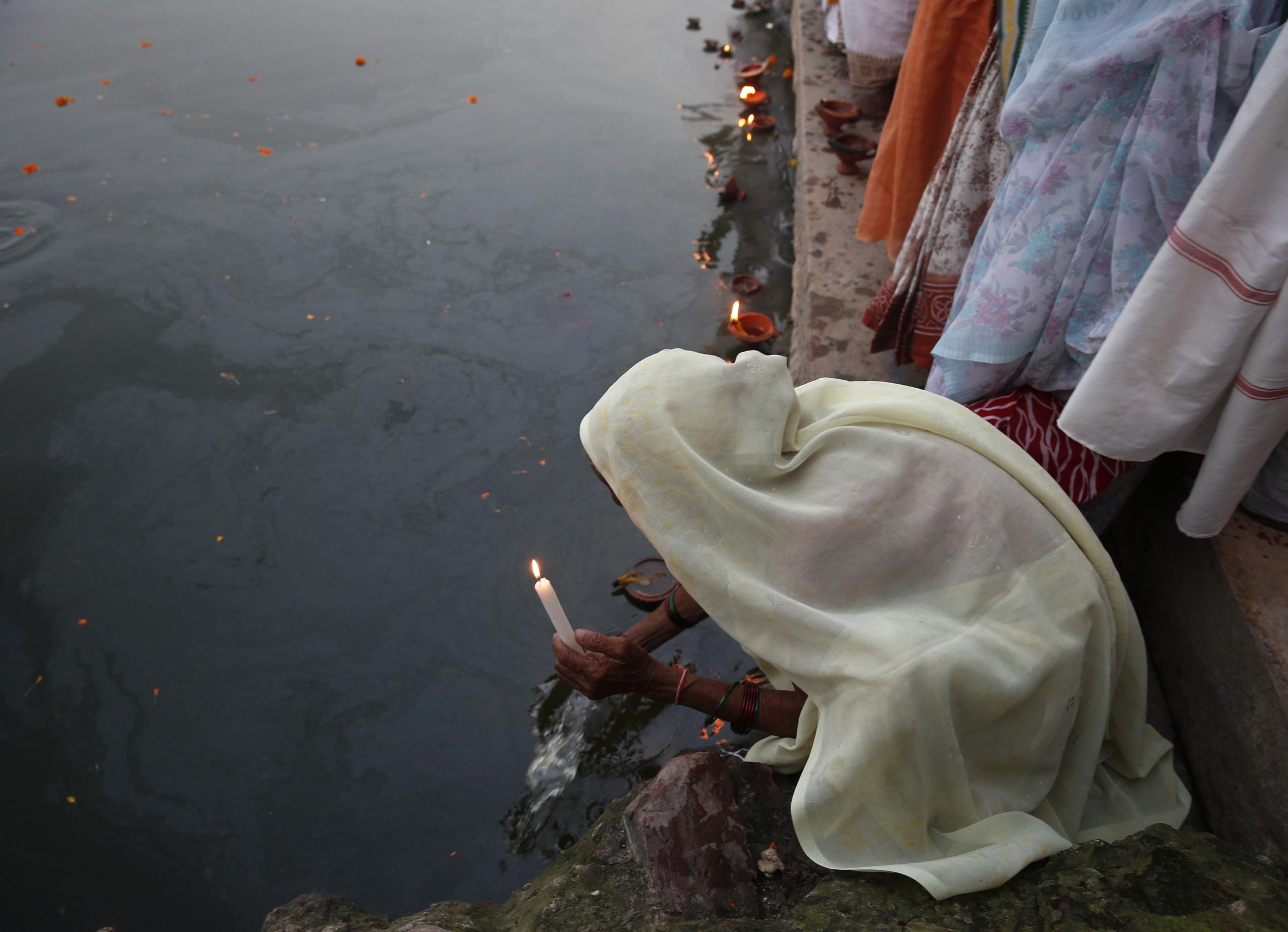 A widow, who was abandoned by her family, holds an earthen oil lamp while offering prayers on the banks of the river Yamuna as part of Diwali celebrations in the northern Indian state of Uttar Pradesh October 21, 2014. 
