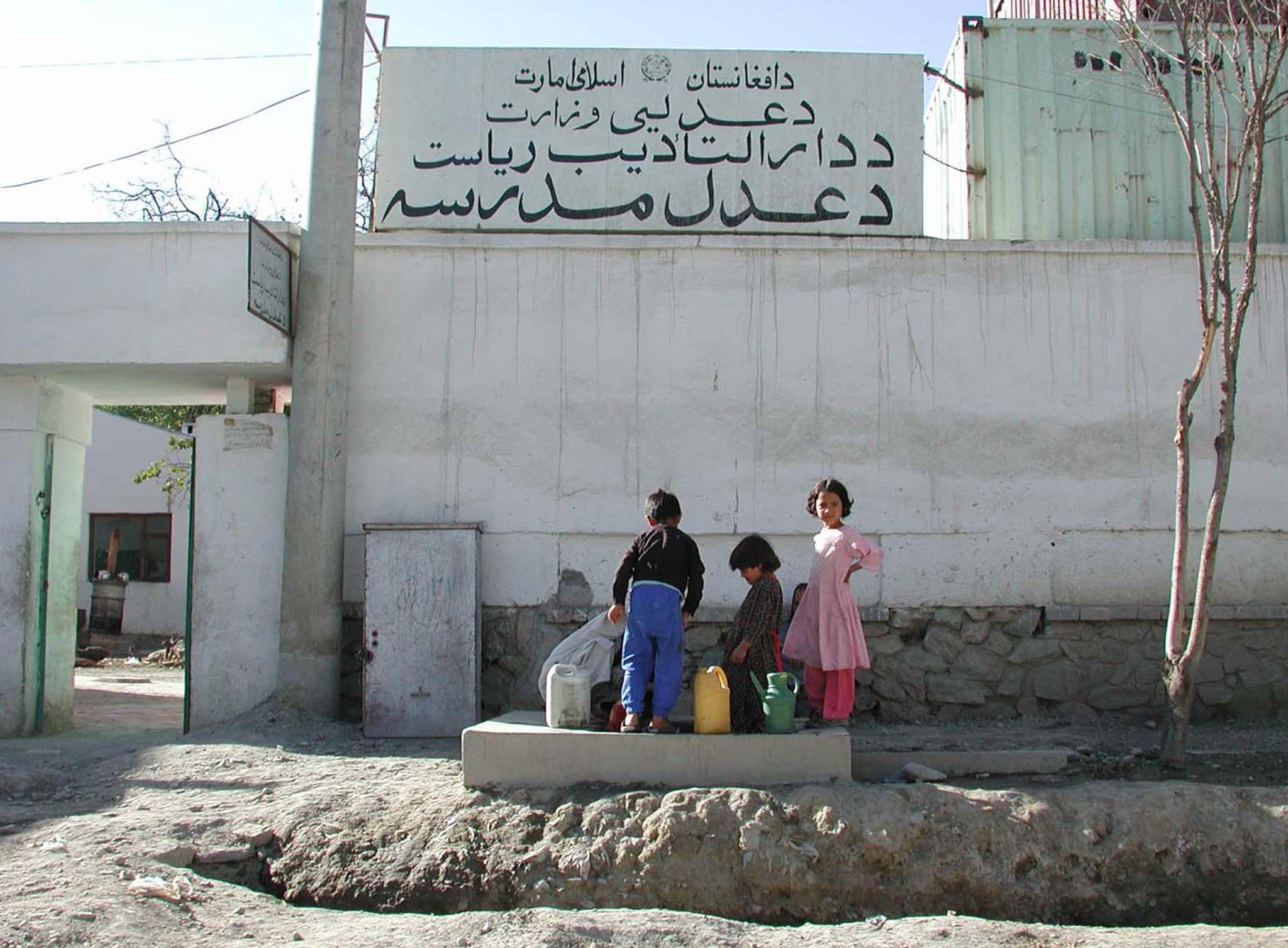 Afghan children collect water from a hand-pump well outside the detention center where eight foreign nationals are believed to be held by the ruling Taliban September 29, 2001. 