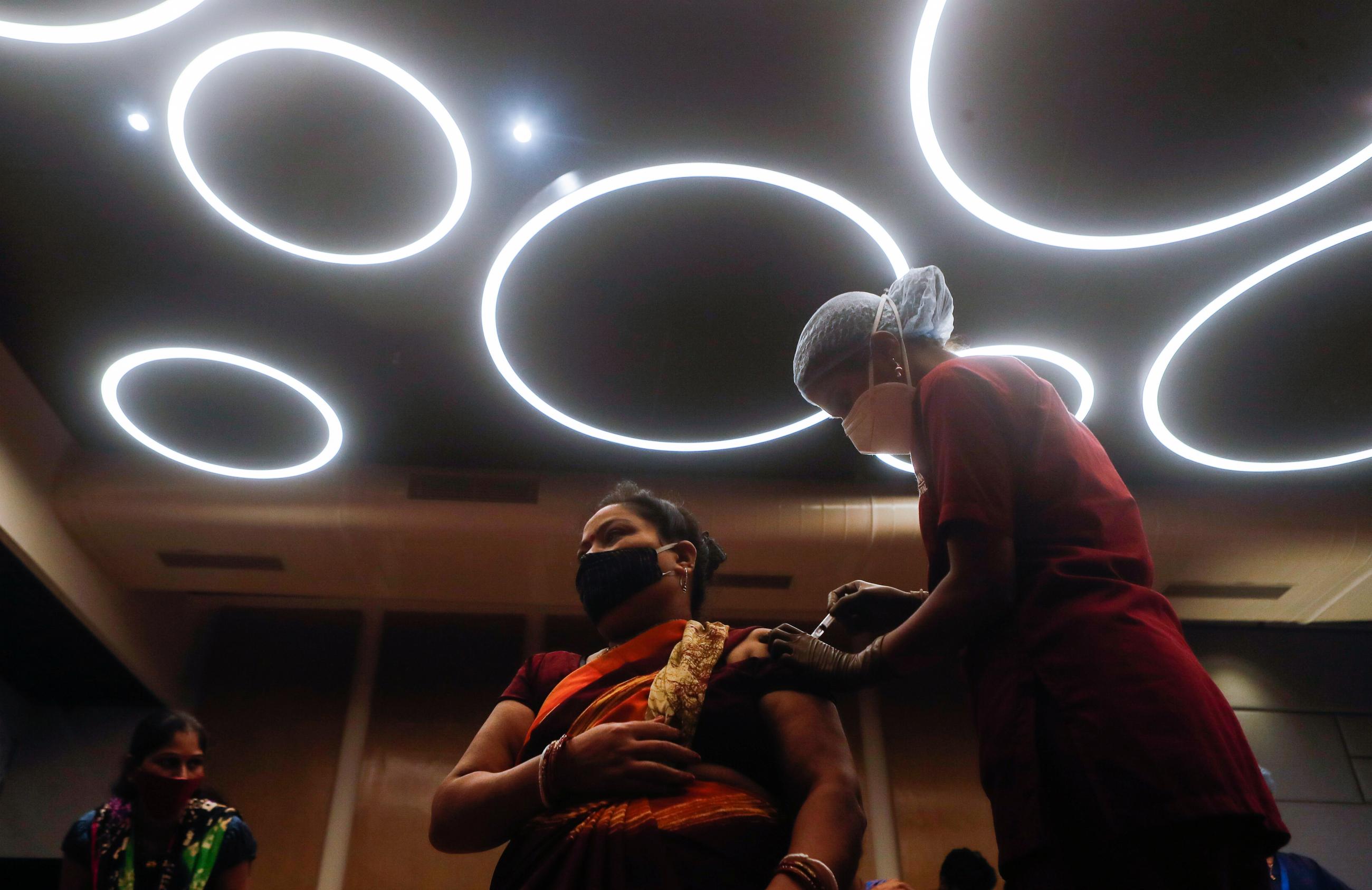 A woman reacts as she receives a dose of COVISHIELD, a vaccine against coronavirus disease (COVID-19) manufactured by Serum Institute of India, at a shopping mall in Mumbai, India, August 11, 2021.