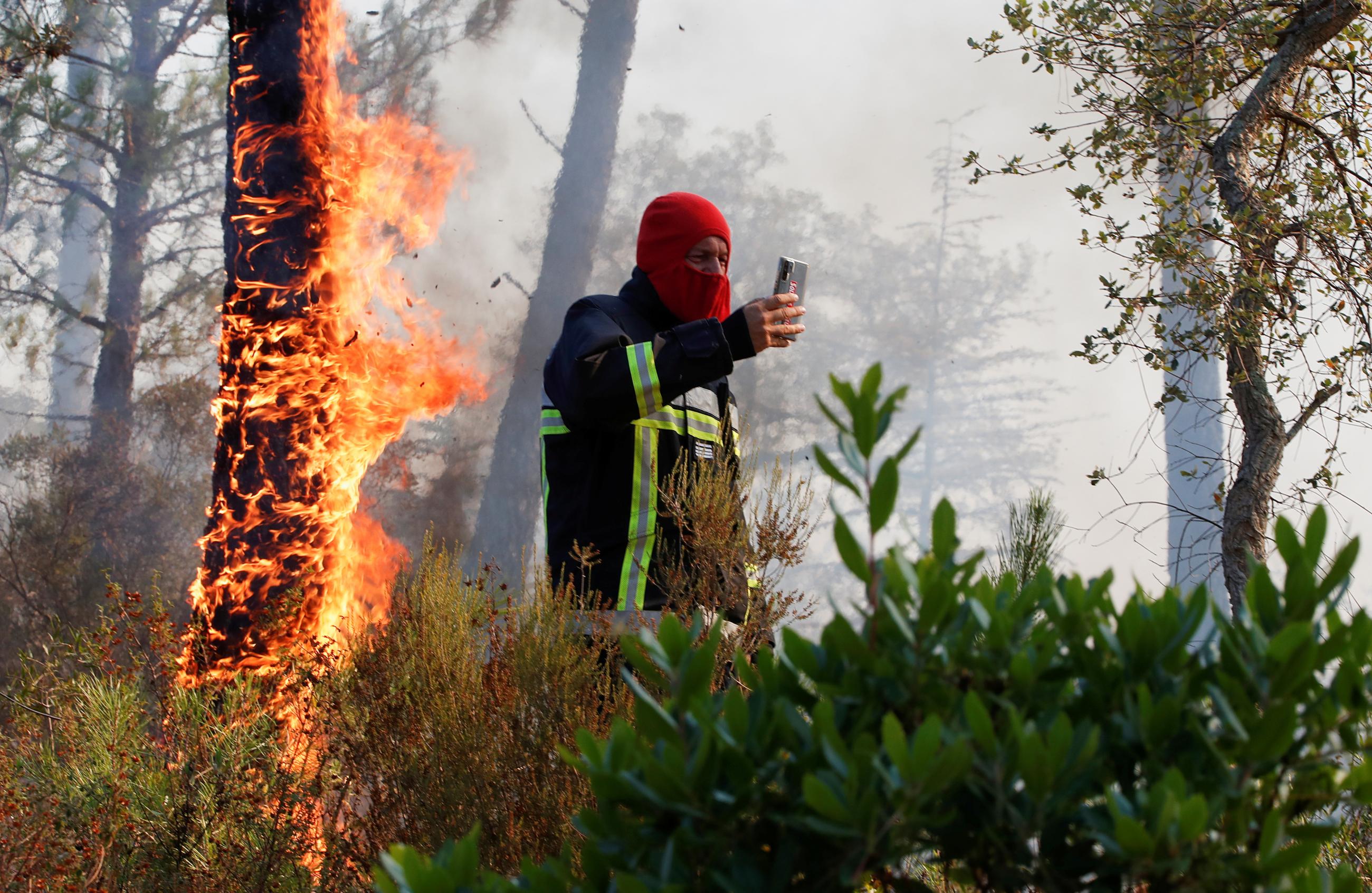 A firefighter takes a picture of a fire during a major wildfire that broke out in Vidauban, in the Var region of southern France, on August 18, 2021