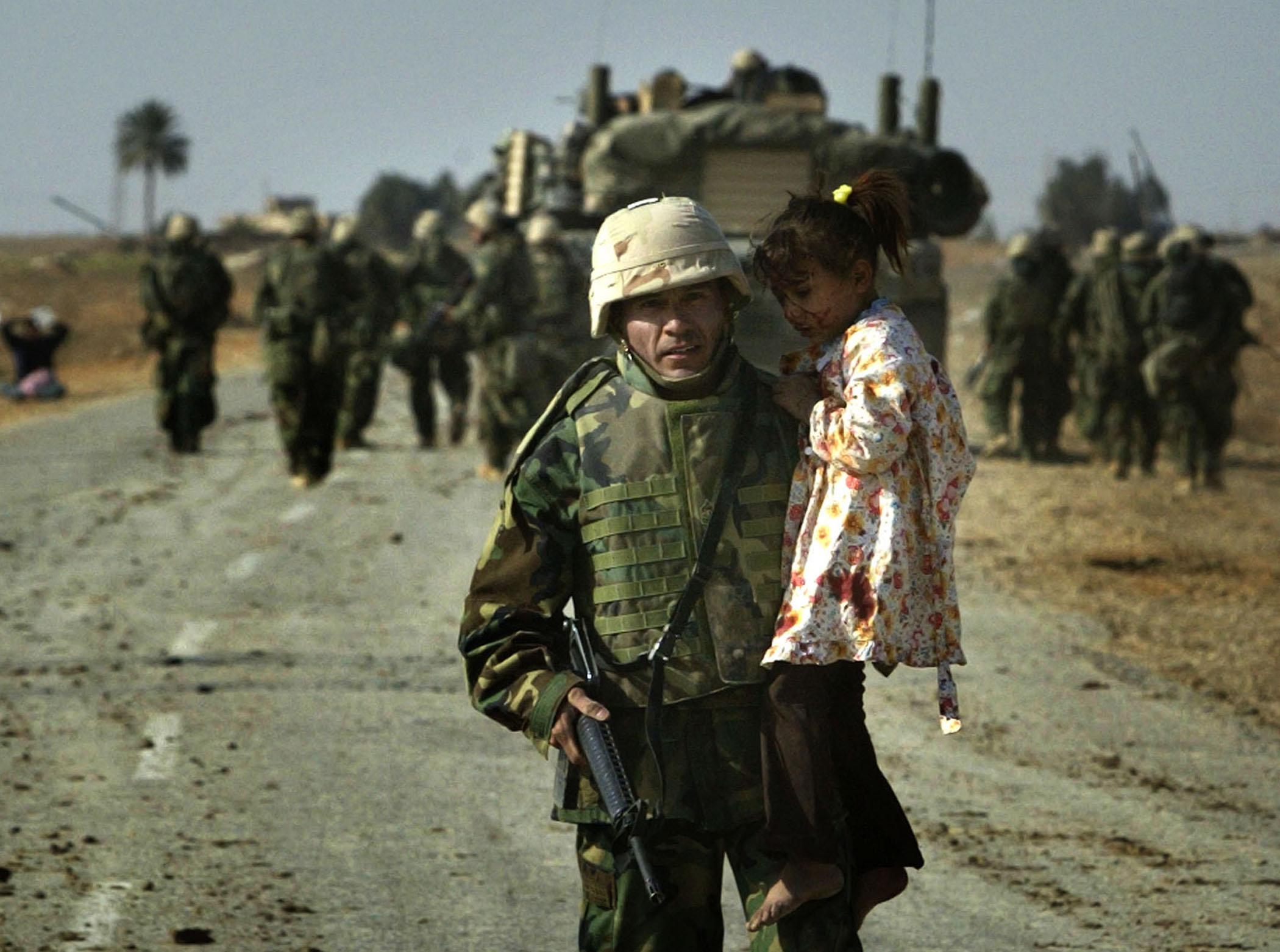 A U.S. marine carries a wounded Iraqi girl from a shooting scene in central Iraq March 29, 2003. Confused front line crossfire ripped apart an Iraqi family on Saturday after local soldiers appeared to force civilians towards U.S. marines positions. 