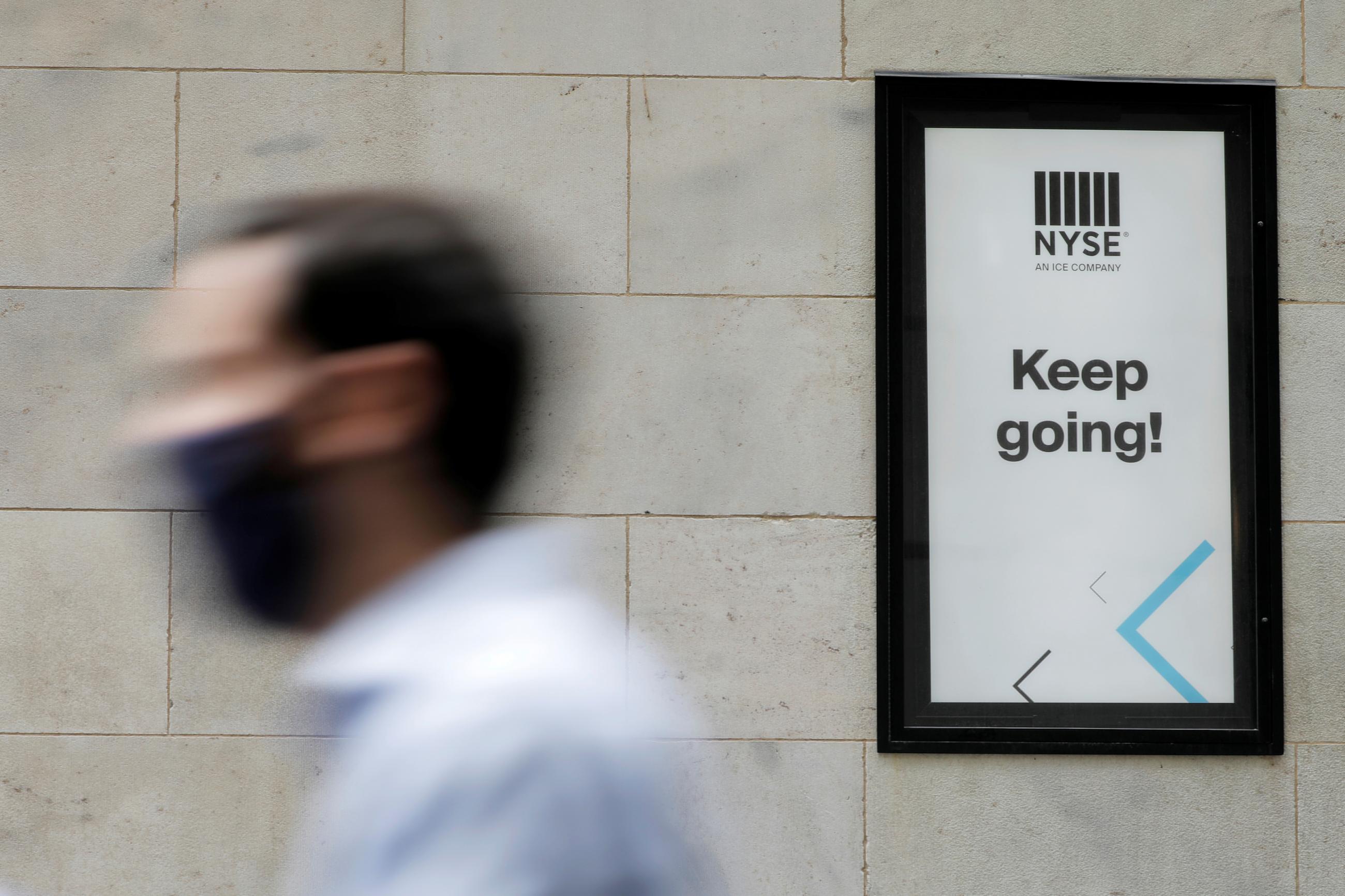 A person in a face mask walks by the New York Stock Exchange (NYSE) during the outbreak of the coronavirus disease (COVID-19) in New York City, New York, U.S., July 19, 2021