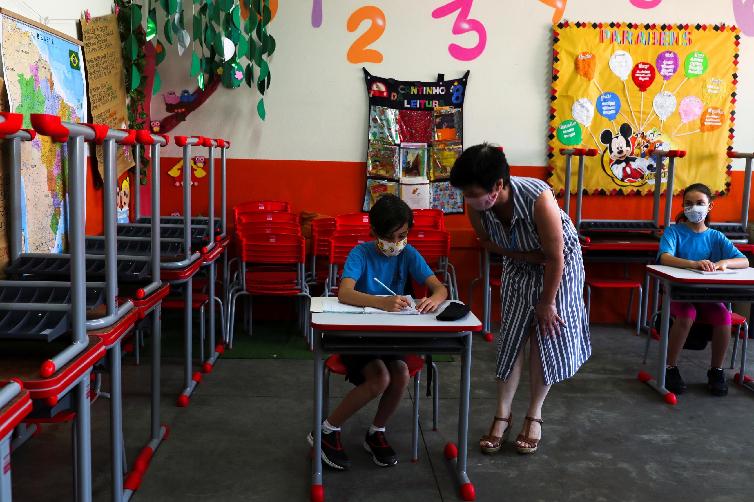 Teacher Eliane Conconi talks to a child in a cheerfully decorated classroom at Thomaz Rodrigues Alckmin school in Sao Paulo, Brazil, on October 7, 2020.