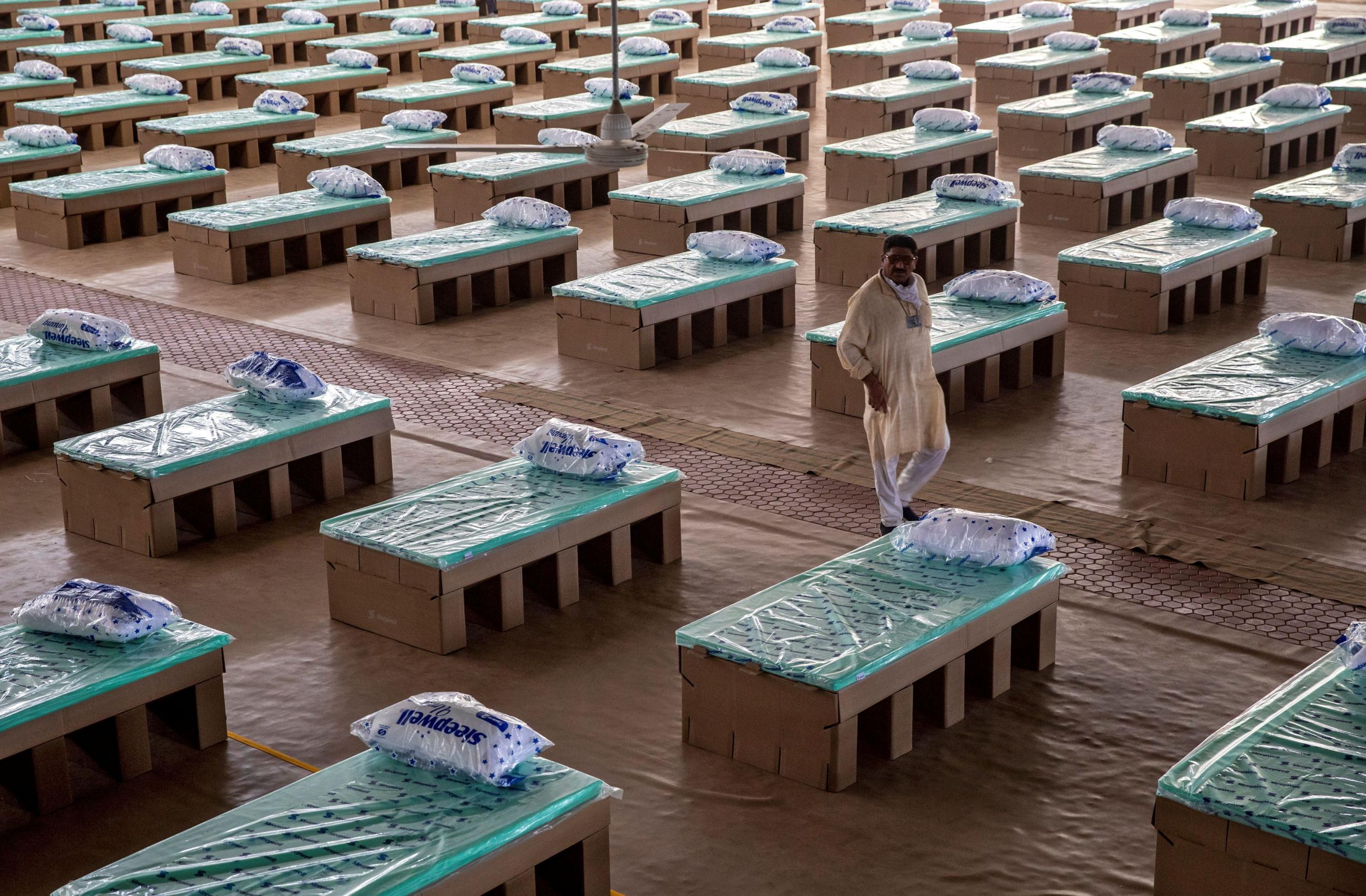 A volunteer walks past disposable beds made out of cardboard at the campus of Radha Soami Satsang Beas, a spiritual organization, where a coronavirus disease (COVID-19) care centre has been constructed for the patients amidst the spread of the disease, in New Delhi, India, on June 26, 2020.