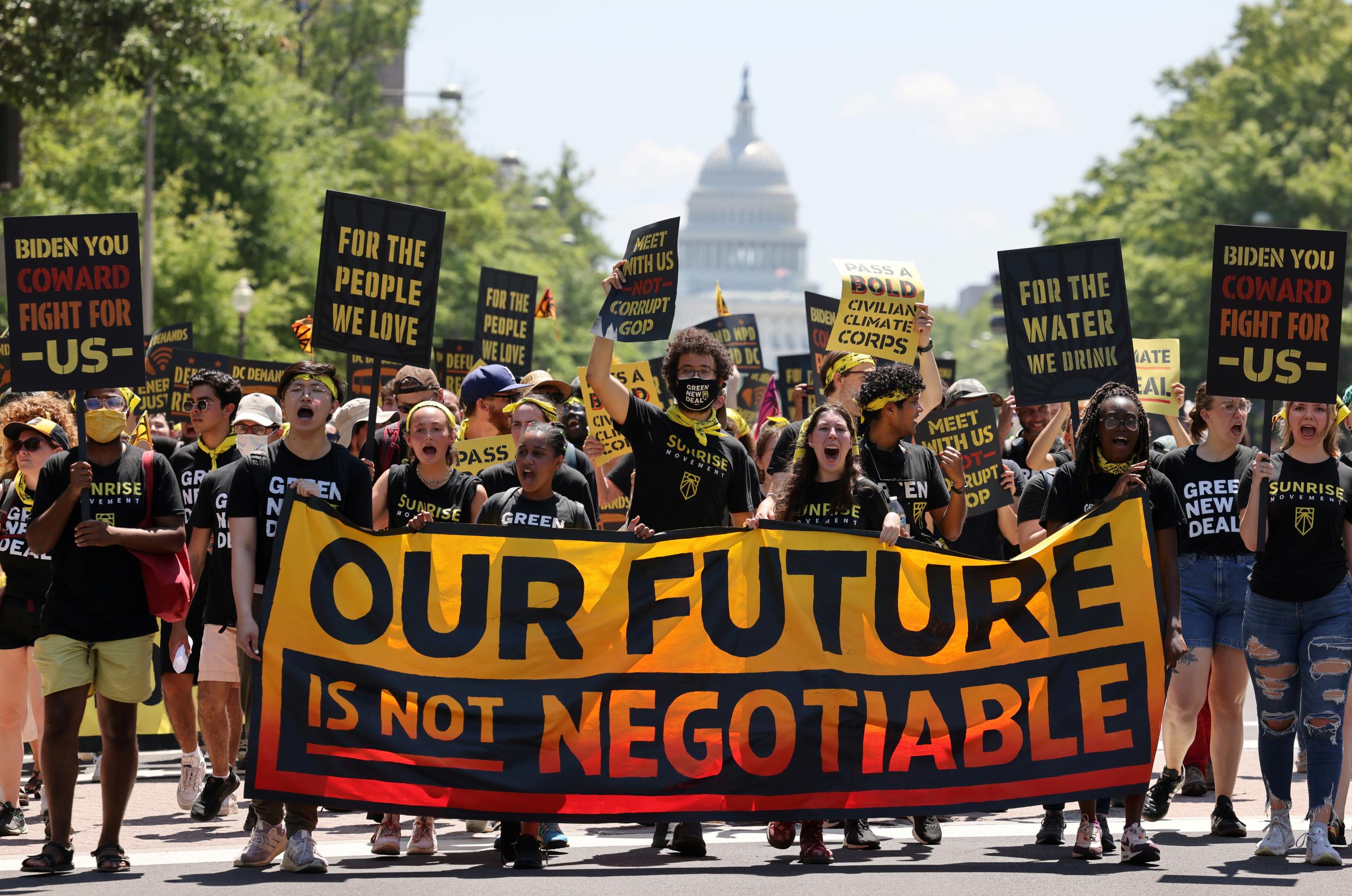 Demonstrators display signs and a banner during a "No Climate, No Deal" march on the White House, in Washington, DC, on June 28, 2021.