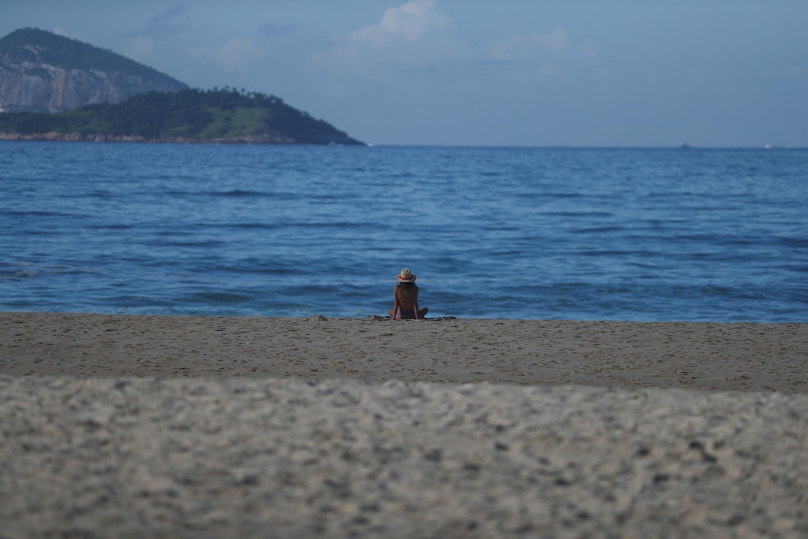 A woman sits at the shore of the Ipanema beach following the closure of the beaches, amid the coronavirus disease (COVID-19) outbreak, in Rio de Janeiro, Brazil, on March 25, 2020.