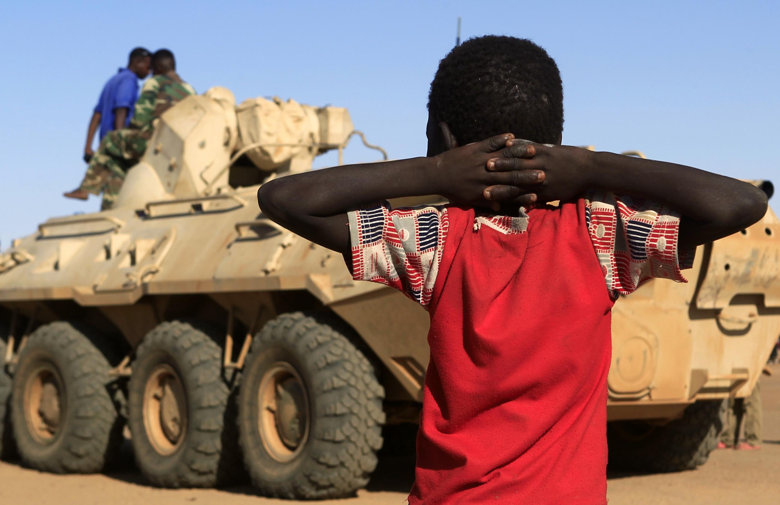 A boy looks on as a military convoy of government forces accompanying Special Prosecutor for Crimes in Darfur, arrives in Tabit village, in North Darfur, Sudan, on November 20, 2014.