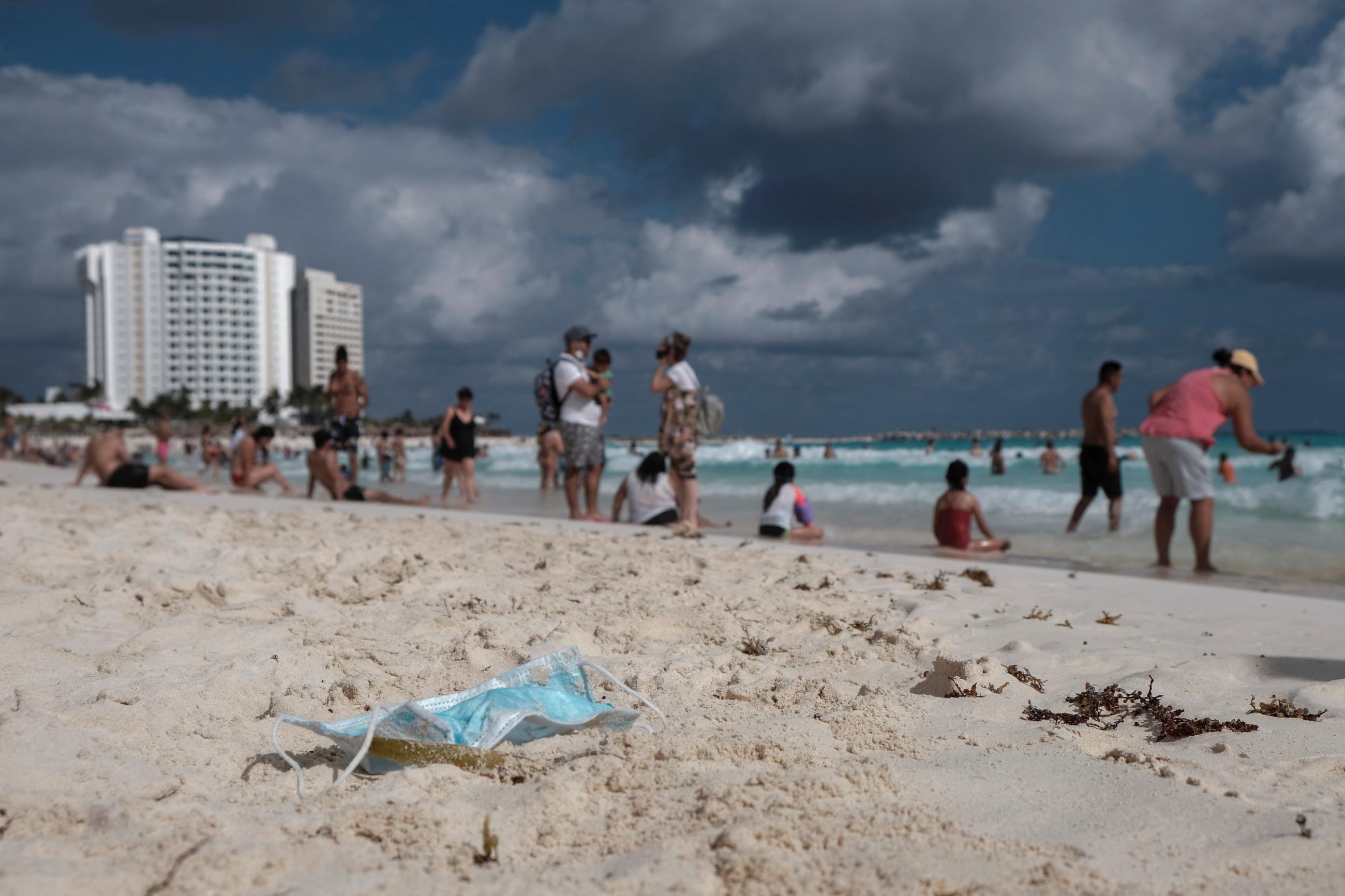 A mask lies on the sand while tourists enjoy a beach as the coronavirus disease (COVID-19) pandemic continues, in Cancun, Mexico December 27, 2021.
