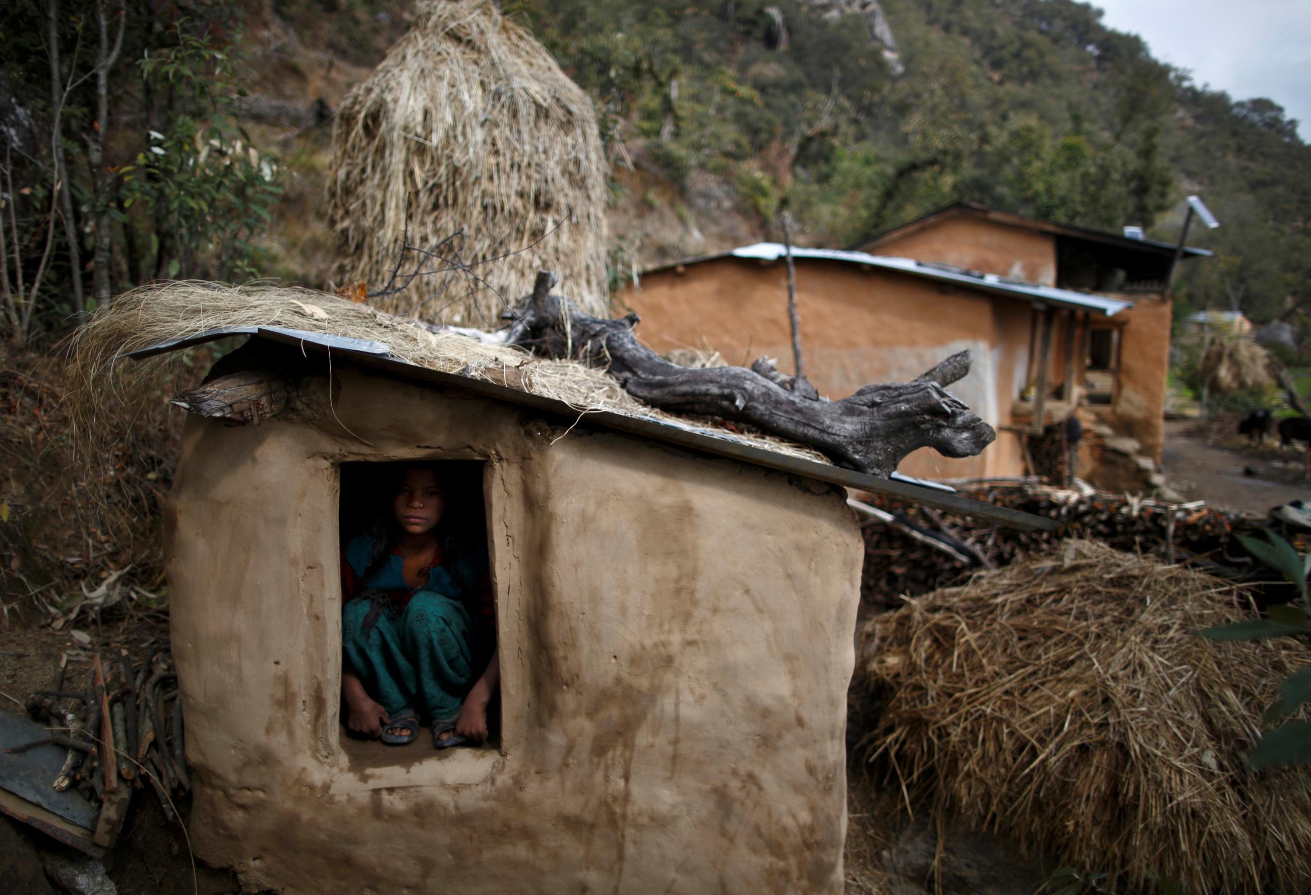 A young woman sits inside a Chaupadi shed in the hills of Legudsen village in Achham District in western Nepal, February 16, 2014