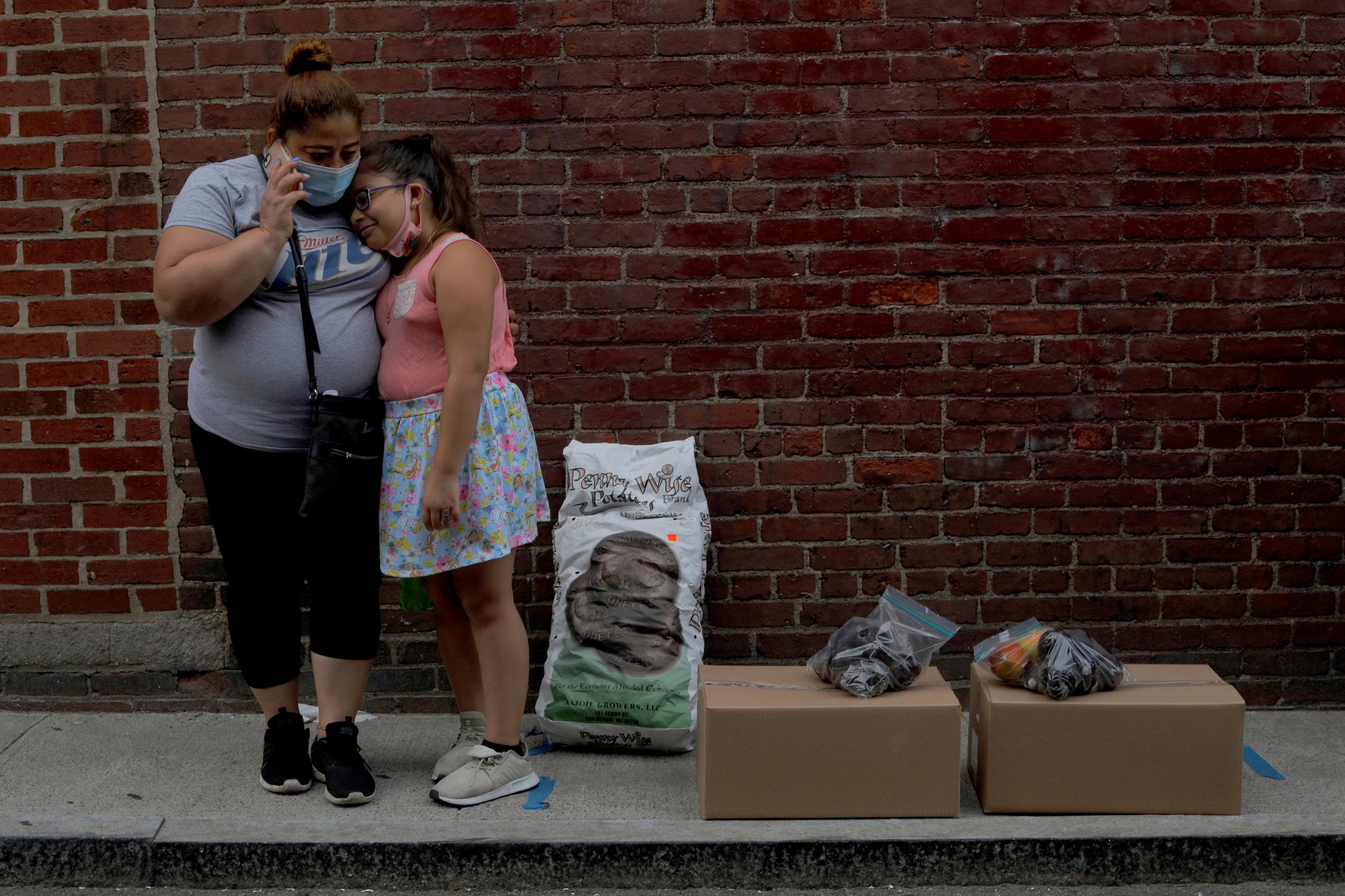 Sandra Cruz, who lost her job because of the coronavirus disease (COVID-19) outbreak, and fell four months behind on her rent and is fearing eviction, and her daughter Gabriella wait for a ride after picking up free groceries distributed by the Chelsea Collaborative in Chelsea, Massachusetts, U.S., July 22, 2020.
