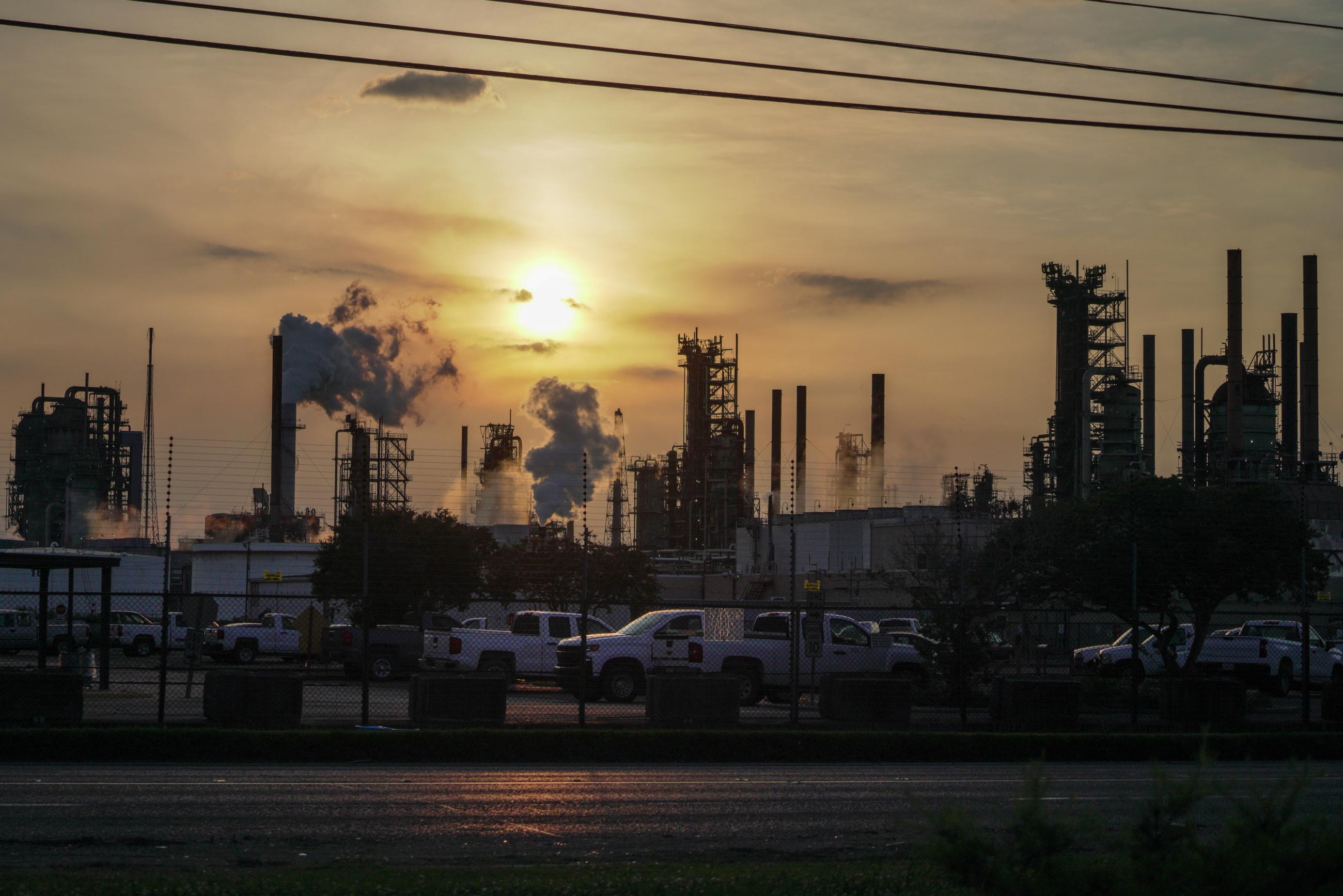 An ExxonMobil refinery, pumping out clouds of soot, is silhouetted against the setting sun in Baton Rouge, Louisiana, on May 15, 2021. 