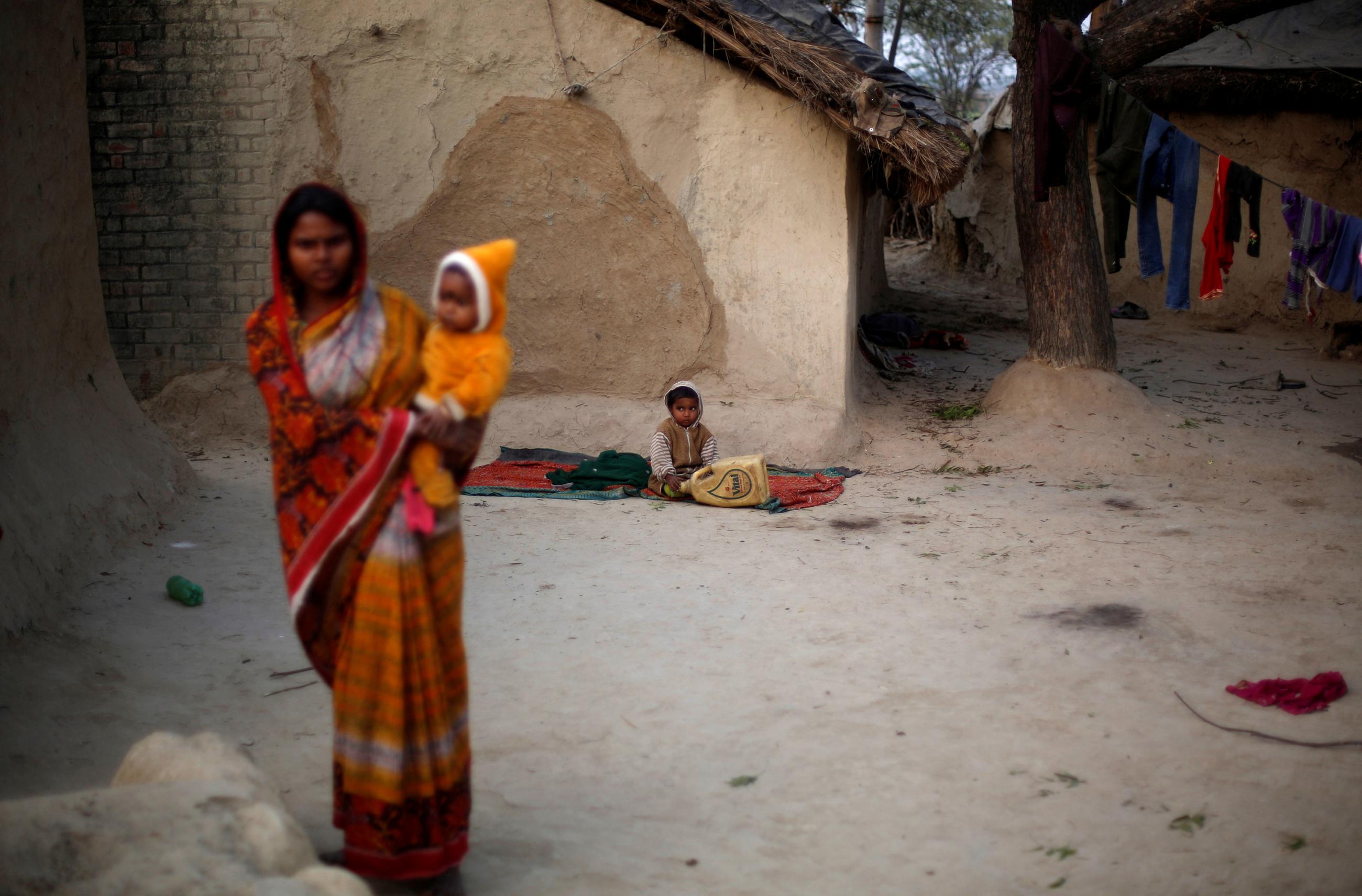 A wife of a snake charmer holds her baby as she stands outside her house in Jogi Dera, Baghpur, Uttar Pradesh, India, on January 16, 2017.