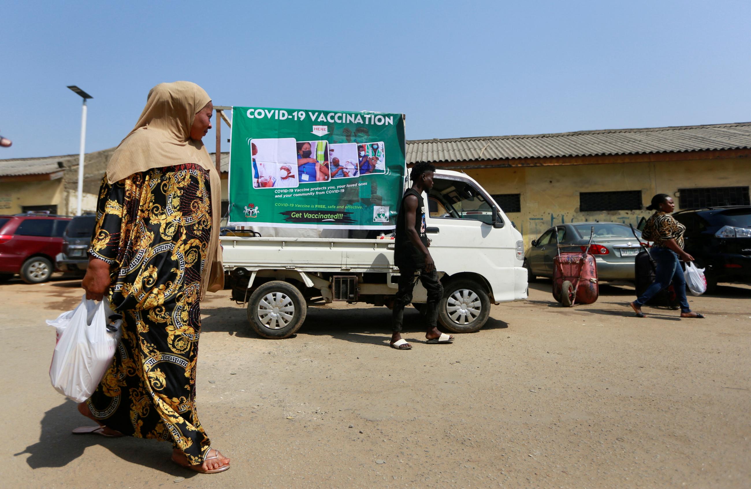 A woman walks past a COVID-19 campaign truck during a mass vaccination exercise at Wuse market in Abuja, Nigeria, on January 26, 2022.