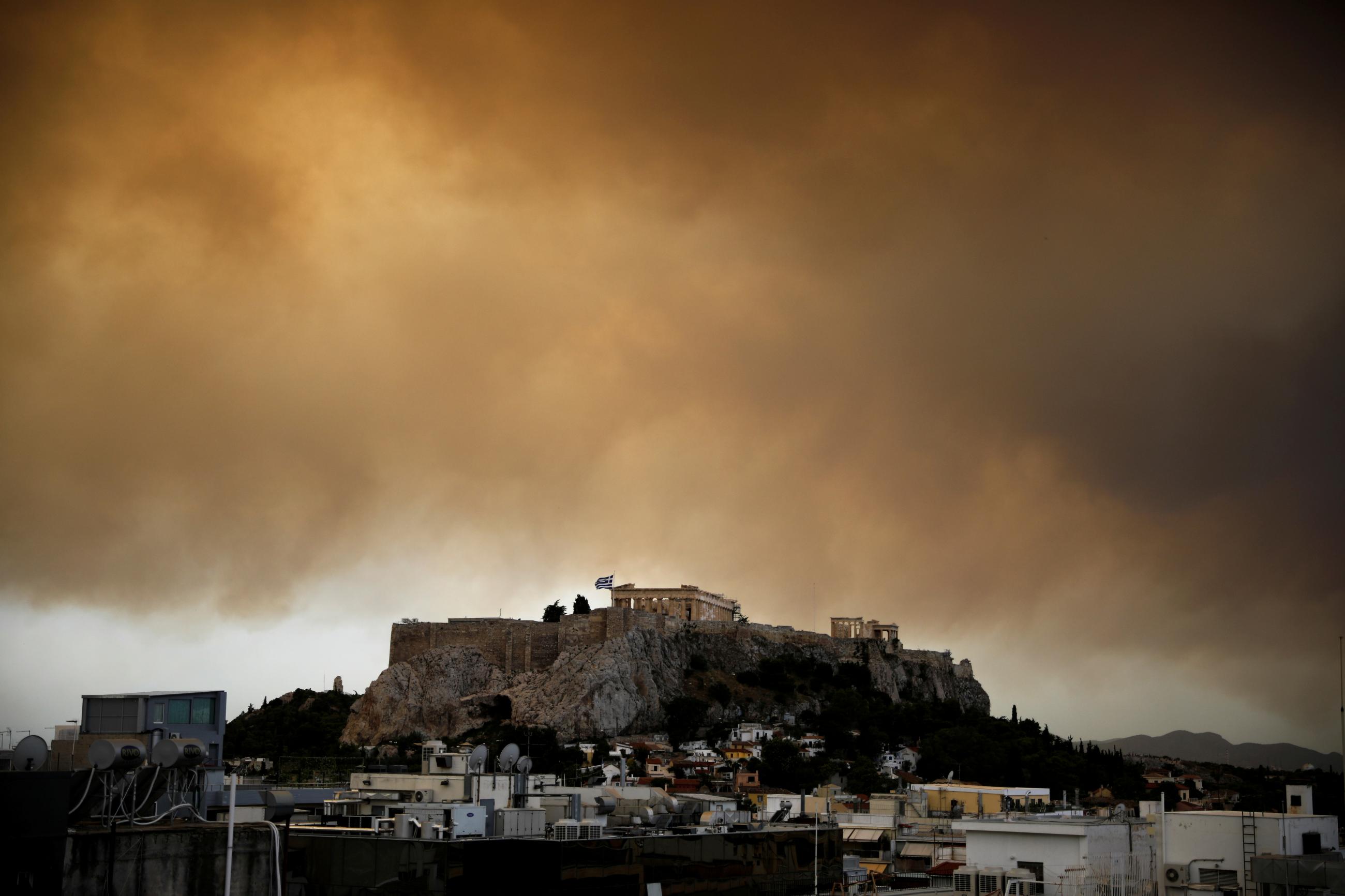 Smoke from a wildfire burning outside Athens is seen over the Parthenon temple atop the Acropolis hill in Athens, Greece, on July 23, 2018. 