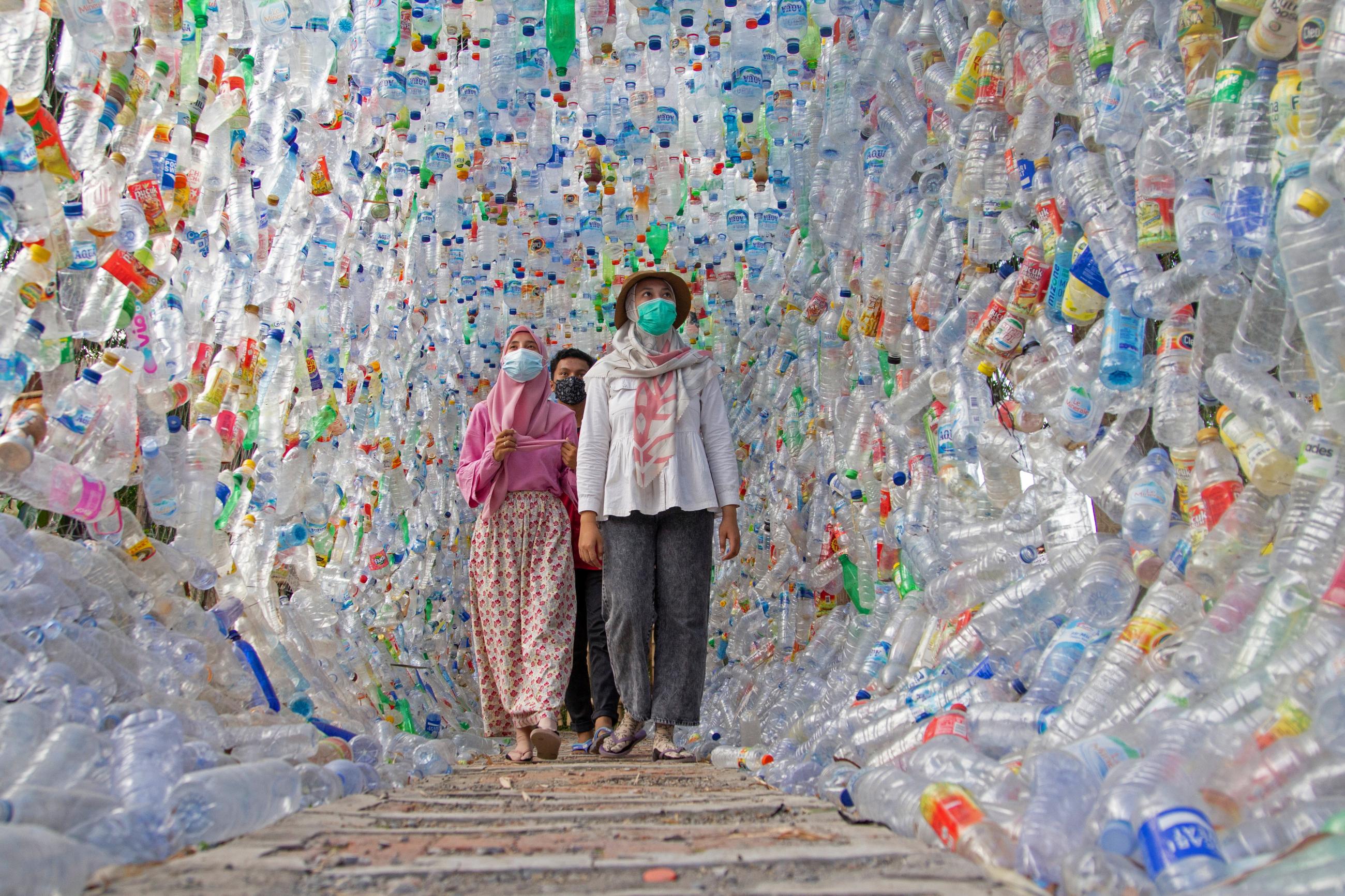 People walk through "Terowongan 4444" or 4444 tunnel, built from plastic bottles collected from several rivers around the city in three years, at the plastic museum constructed by Indonesia's environmental activist group Ecological Observation and Wetlands Conservation (ECOTON) in Gresik regency near Surabaya, East Java province, Indonesia, September 28, 2021.