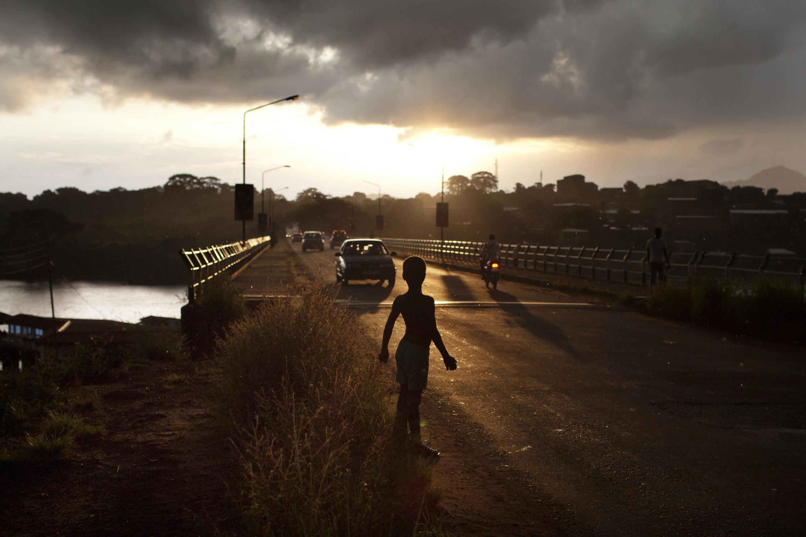 A boy stands on a road at dawn in Freetown, Sierra Leone, November 21, 2012.