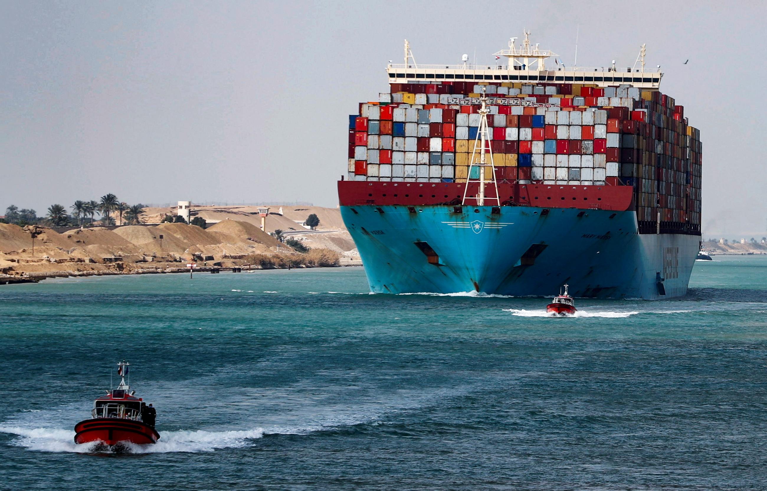 A ship piled with shipping containers passes through the Suez Canal in Suez, Egypt