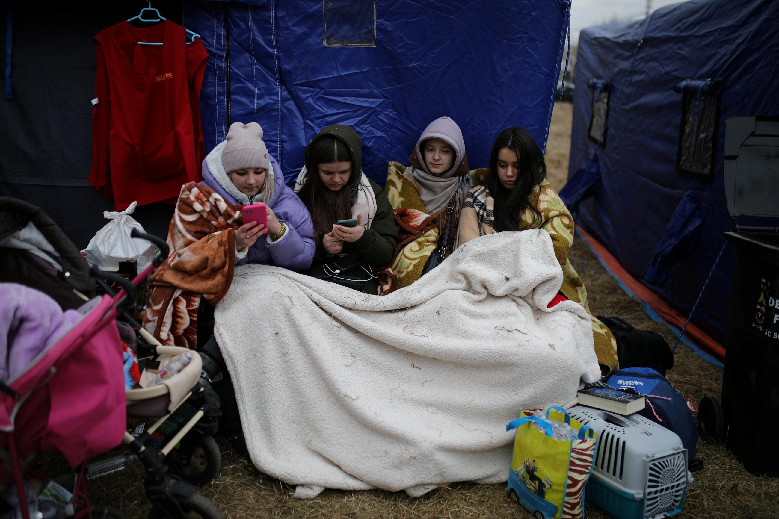 Women cover themselves with a blanket after fleeing from Ukraine to Romania, after Russia launched a massive military operation against Ukraine, at the border crossing in Siret, Romania, February 27, 2022.