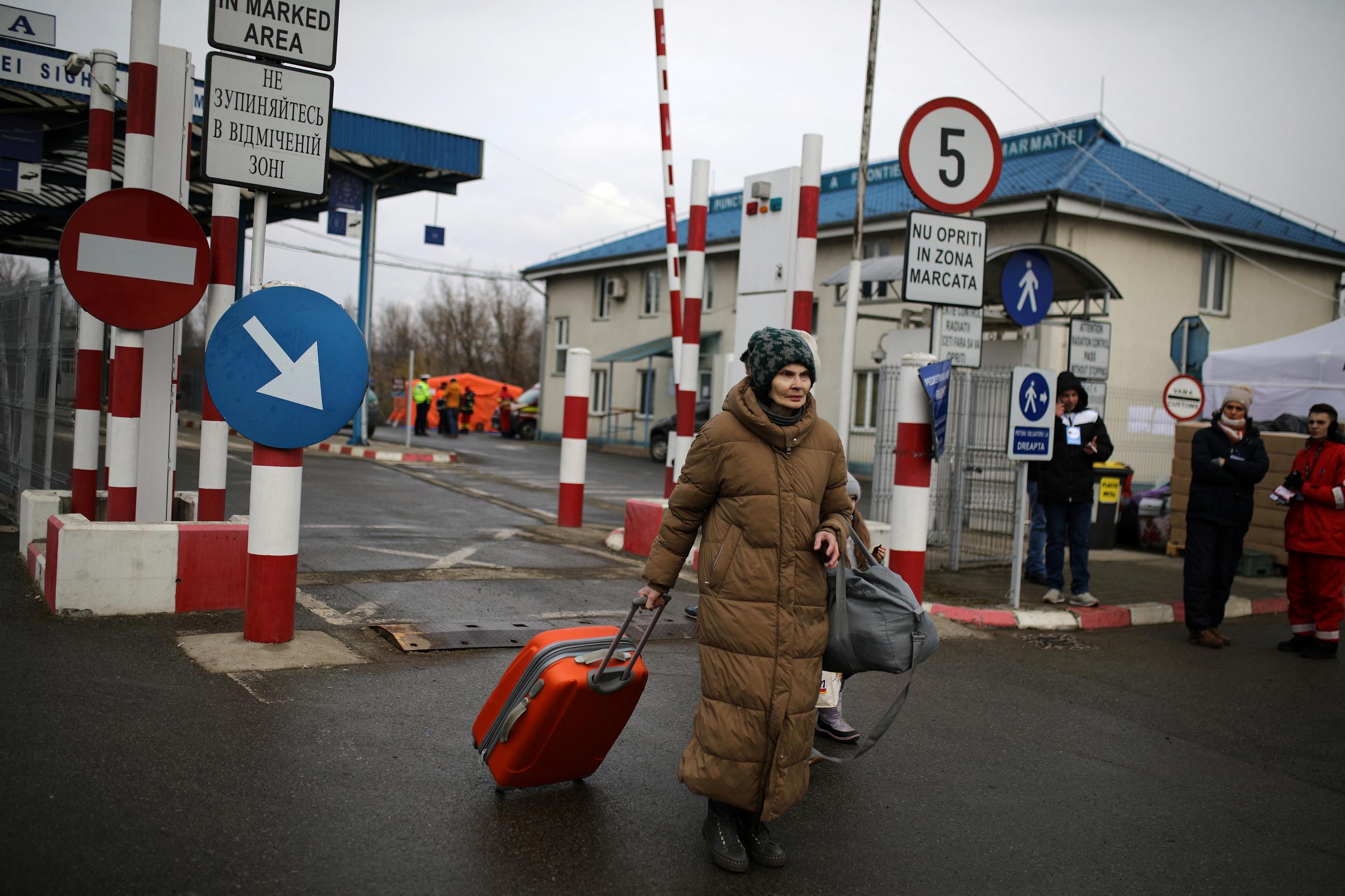 A woman carries her luggage after fleeing from Russia's invasion of Ukraine, at the border crossing in Sighetu Marmatiei, Romania.