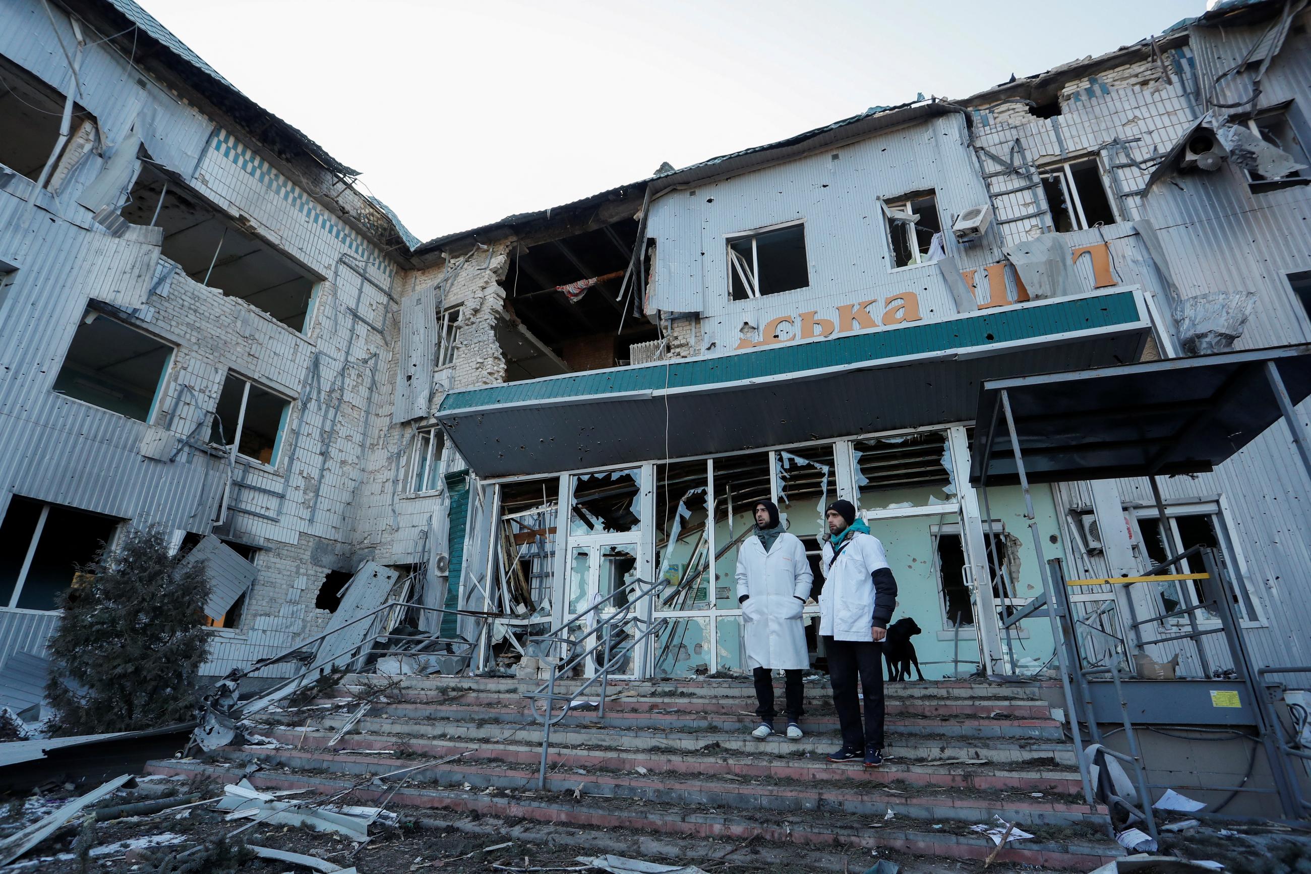 Medical workers stand outside a local hospital, which was destroyed during Russia's war in Ukraine in the Russian-occupied town of Volnovakha in the Donetsk region, Ukraine March 12, 2022. 