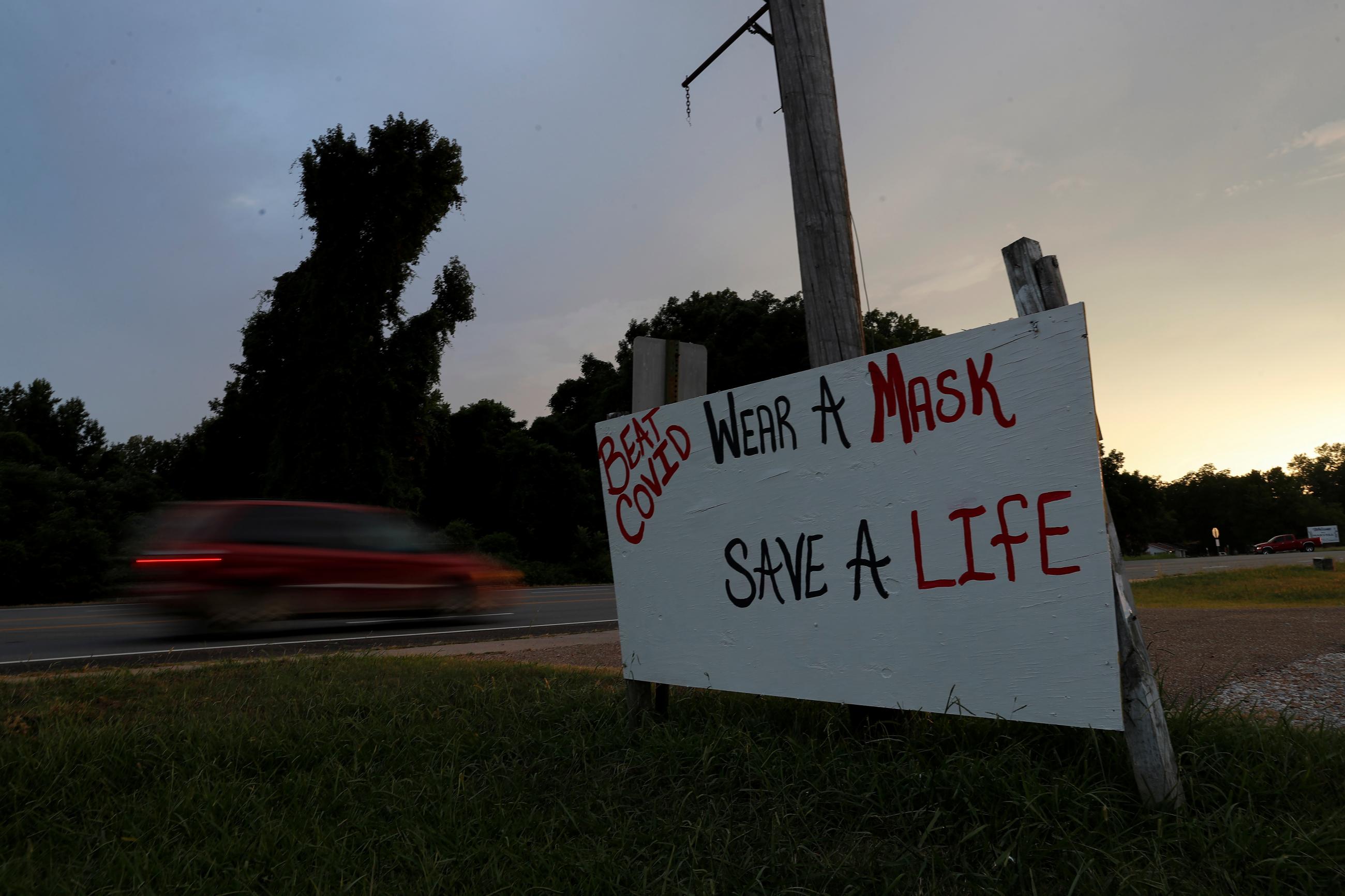 A car drives by a sign asking people to wear masks, amid the coronavirus disease (COVID19) pandemic, along U.S. Route 49 near Marvell, Arkansas, U.S., August 13, 2021