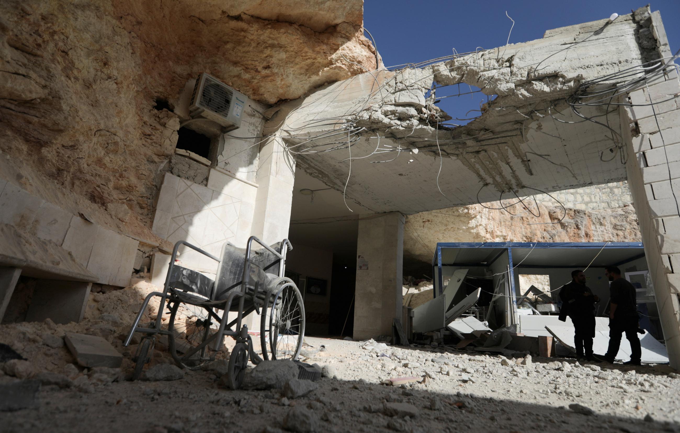 An empty wheel chair stands covered in dust in the remains of a bombed hospital in Atareb, Syria