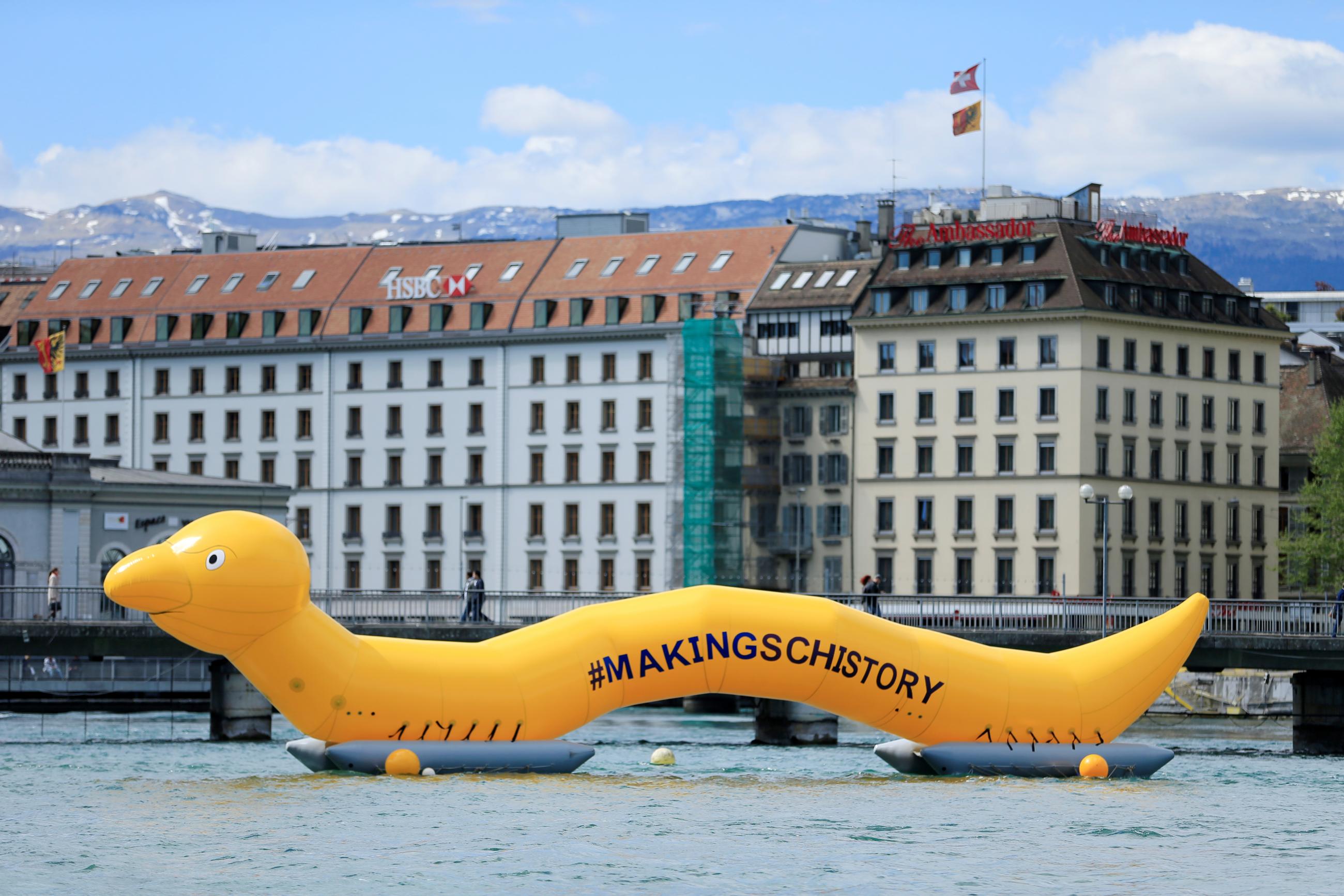 An inflatable yellow worm labled #makingschistory floats on a lake in Geneva, Switzerland to raise awareness for schistosomiasis.