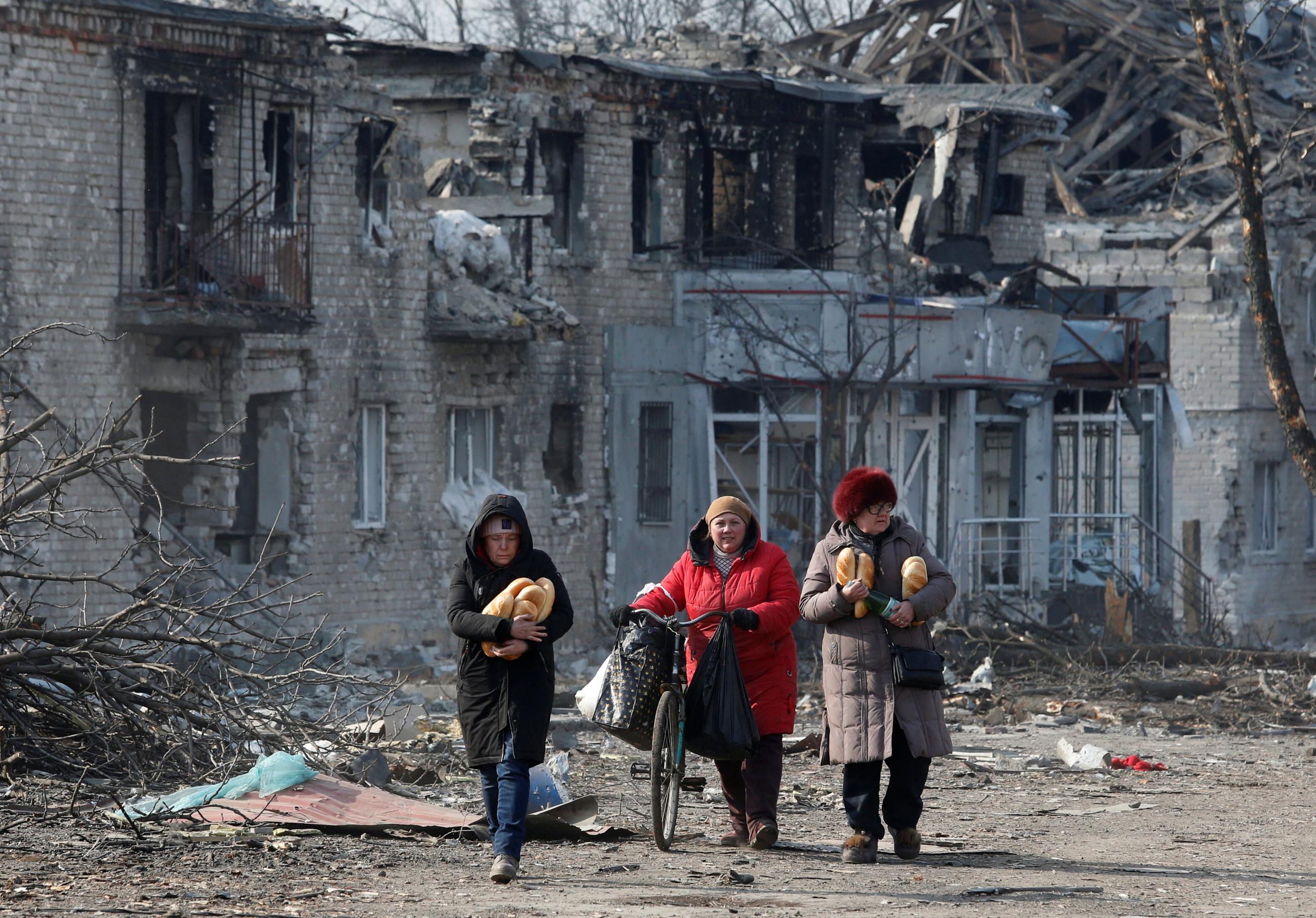 Local residents walk along a street after receiving humanitarian aid during Russia’s attack in the separatist-controlled town of Volnovakha, in the Donetsk region of Ukraine, on March 15, 2022.