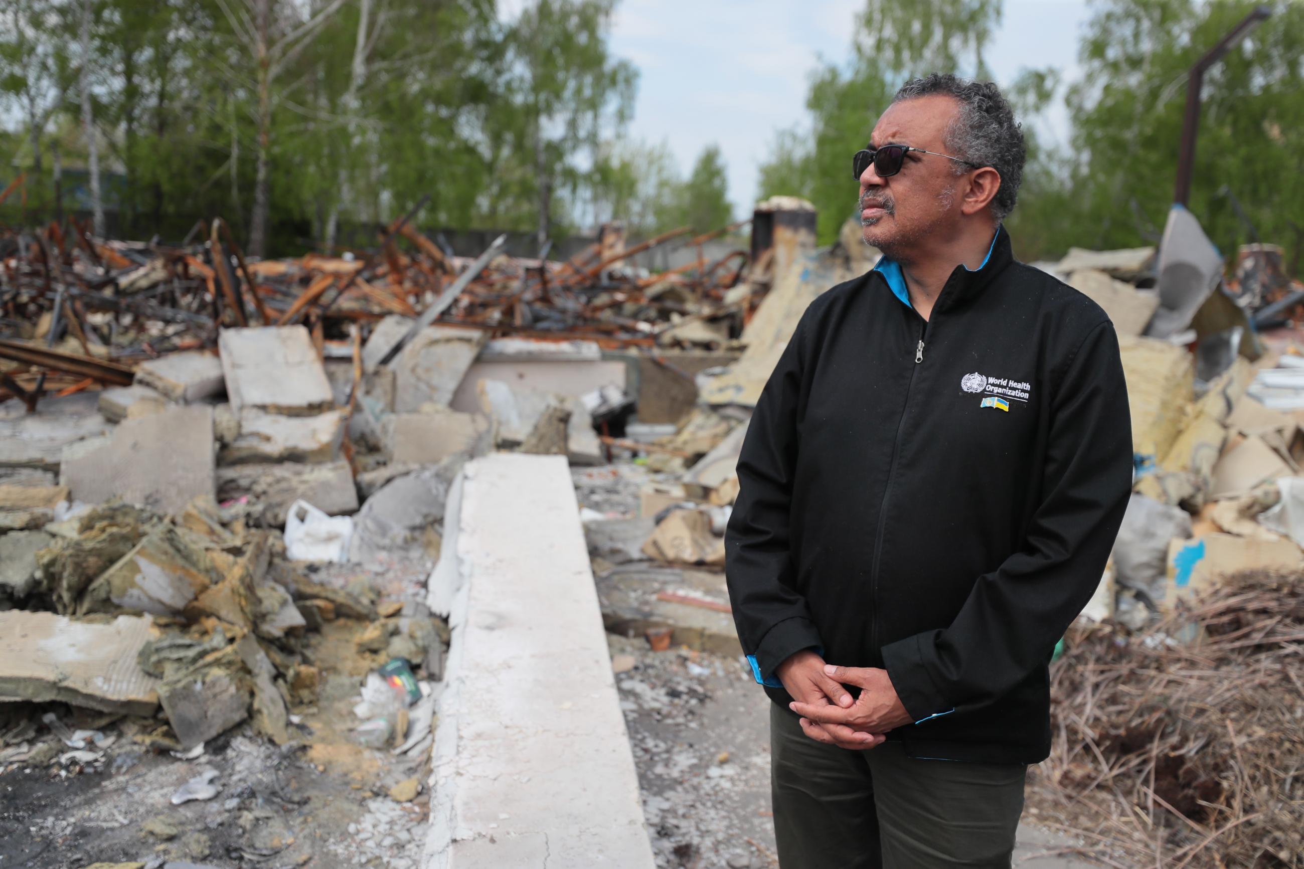World Health Organization Tedros Adhanom Ghebreyesus stands looking pensive in front of a destroyed Primary Health Care center/COVID-19 Vaccination Site near Makariv District Hospital, Ukraine on 07 May 2022.