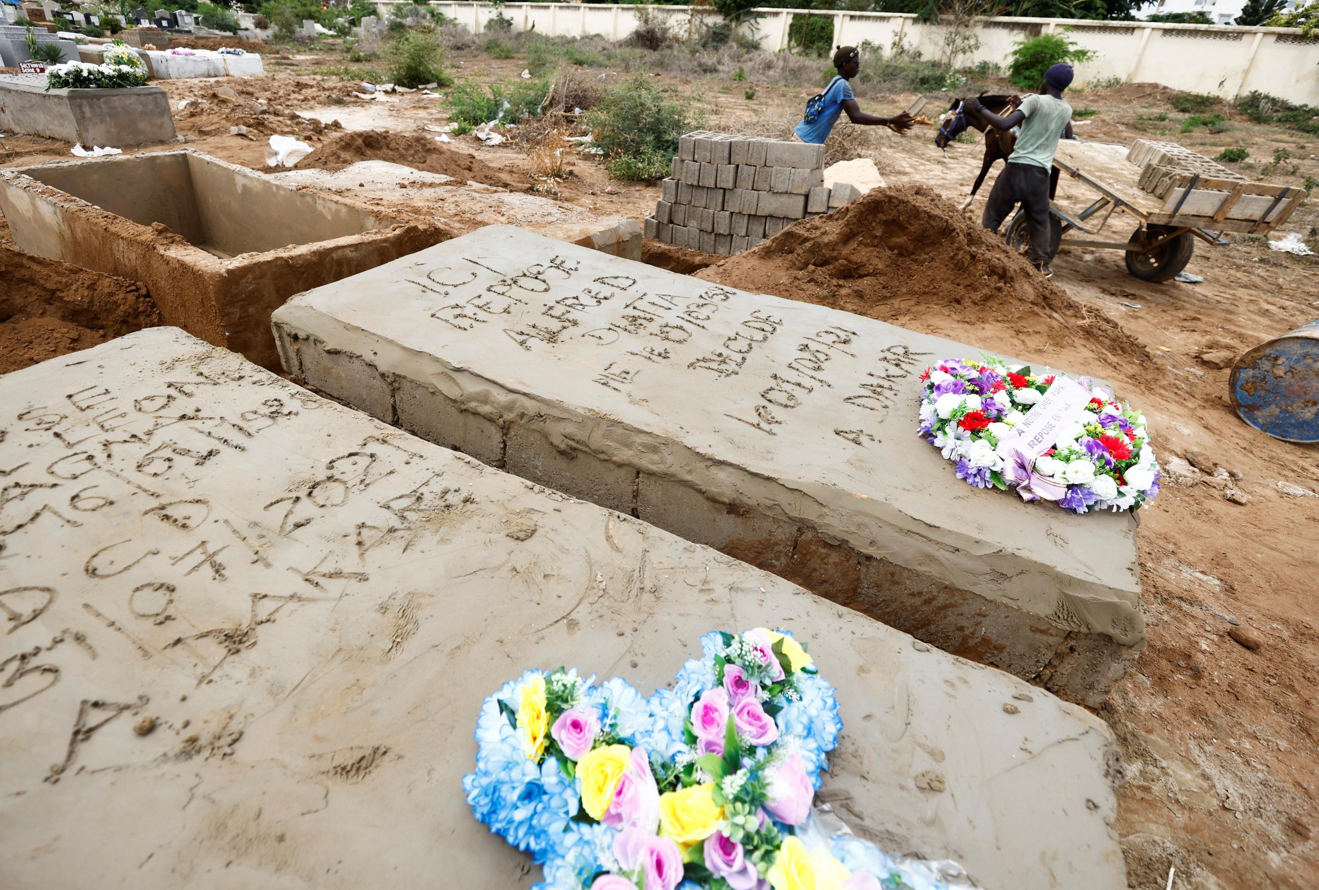 Grave diggers offload bricks next to the grave of a man who, according to his son, died from the coronavirus disease (COVID-19), at the Christian Saint-Lazare Cemetery, as Senegal records more COVID-19 deaths, in Dakar, Senegal, on August 4, 2021.