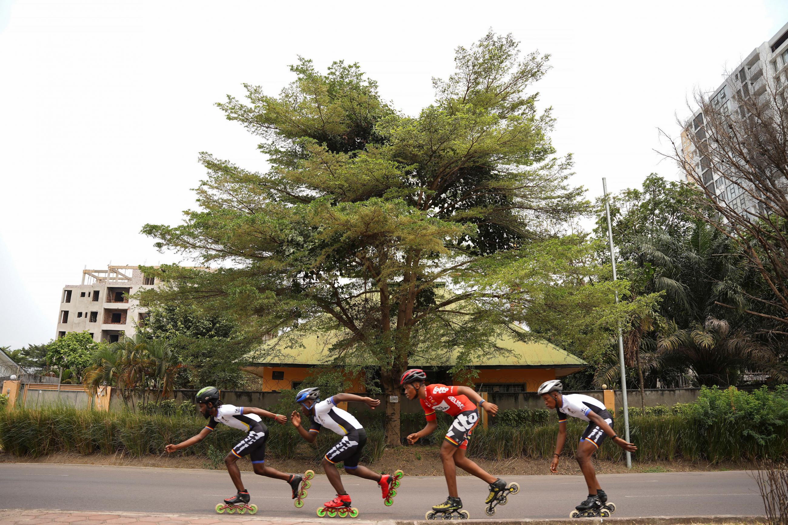 Serge Makolo leads his team of four speed skaters past a large green treeduring a training in Kinshasa, Democratic Republic of Congo, on September 16, 2021. 