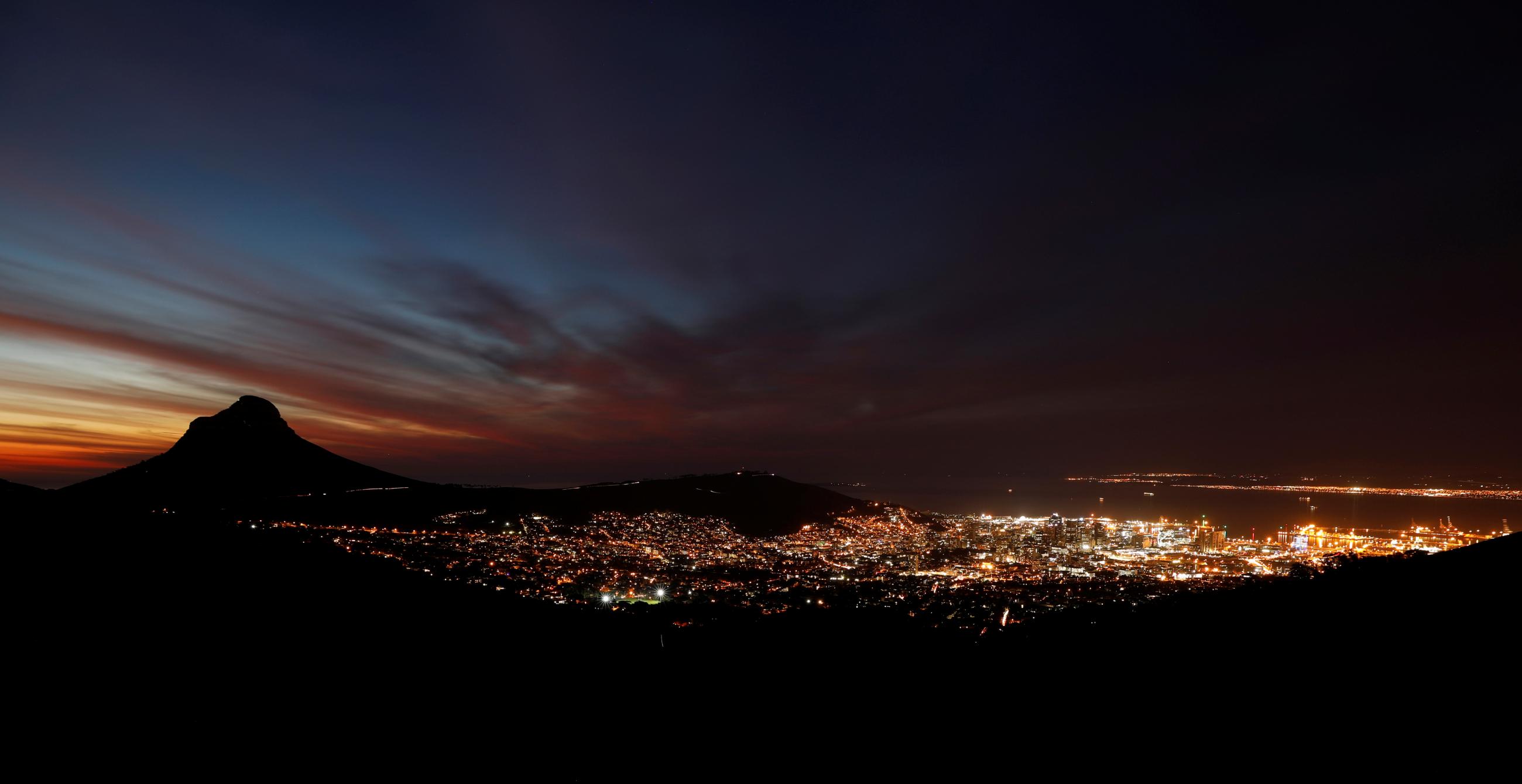 Electricity lights the city as the day's last light fades dark blue over Lion's Head mountain in Cape Town, South Africa, on June 18, 2019.
